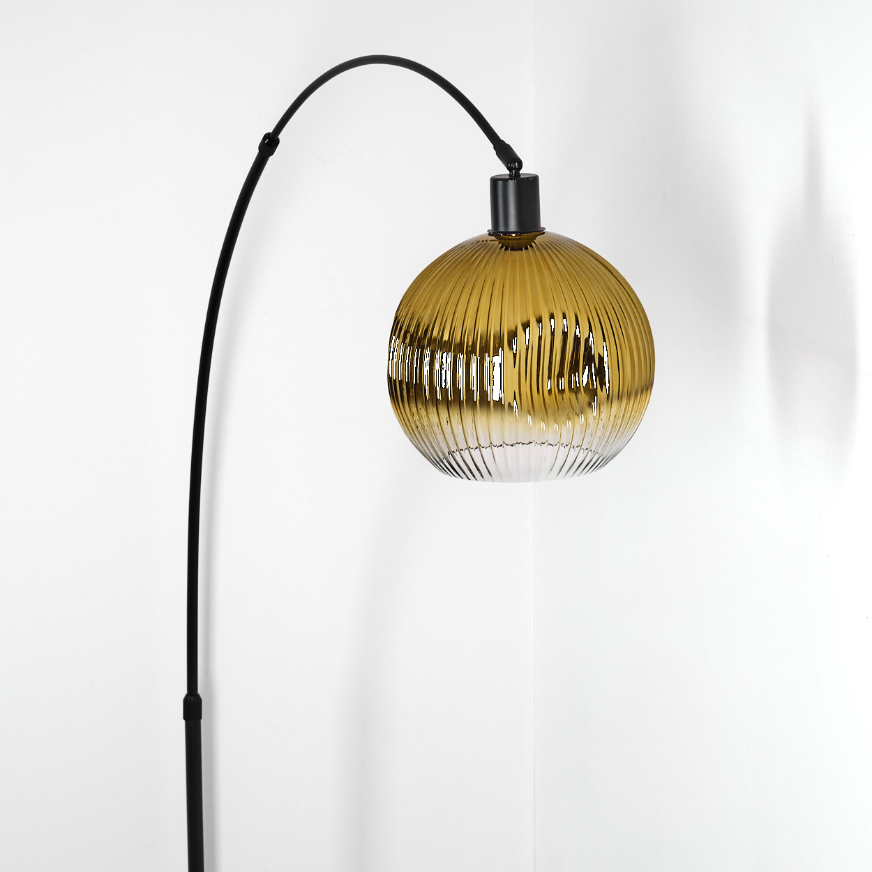 Eine moderne Stehlampe mit einem schwarzen, gebogenen Arm und einem runden, gerippten, bernsteinfarbenen Glasschirm. Der Hintergrund ist weiß.