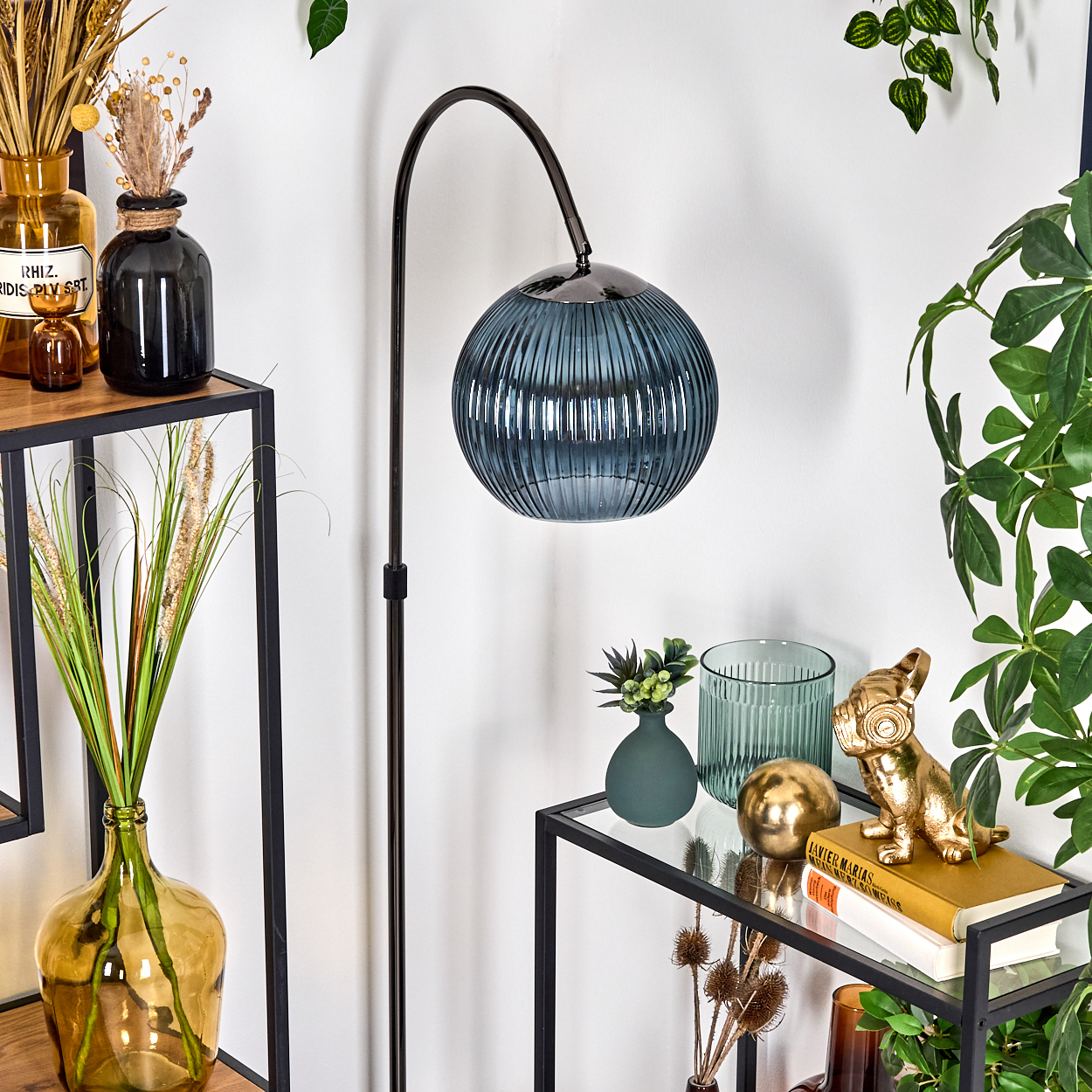 Moderne Inneneinrichtung mit Stehlampe und Dekorationen. Enthält Vasen, eine Hundestatue und Pflanzen, mit weißer Wand im Hintergrund.