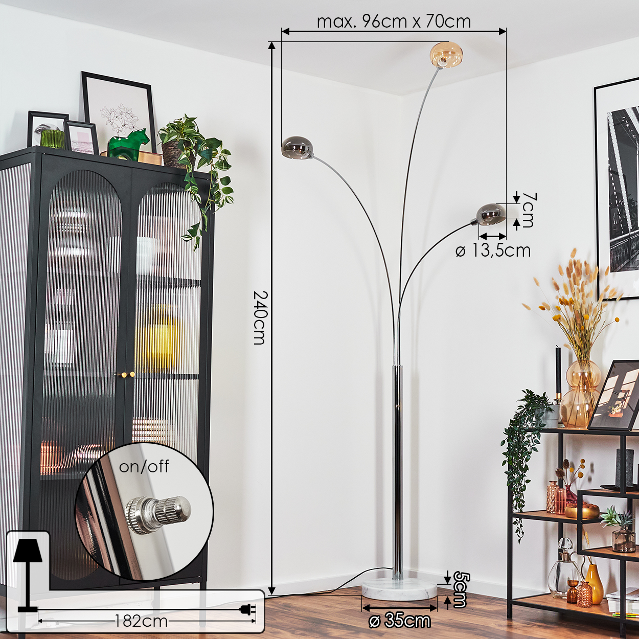 Eine moderne Stehlampe mit drei Glasschirmen. Sie steht neben einem schwarzen Schrank und einem dekorativen Regal.
