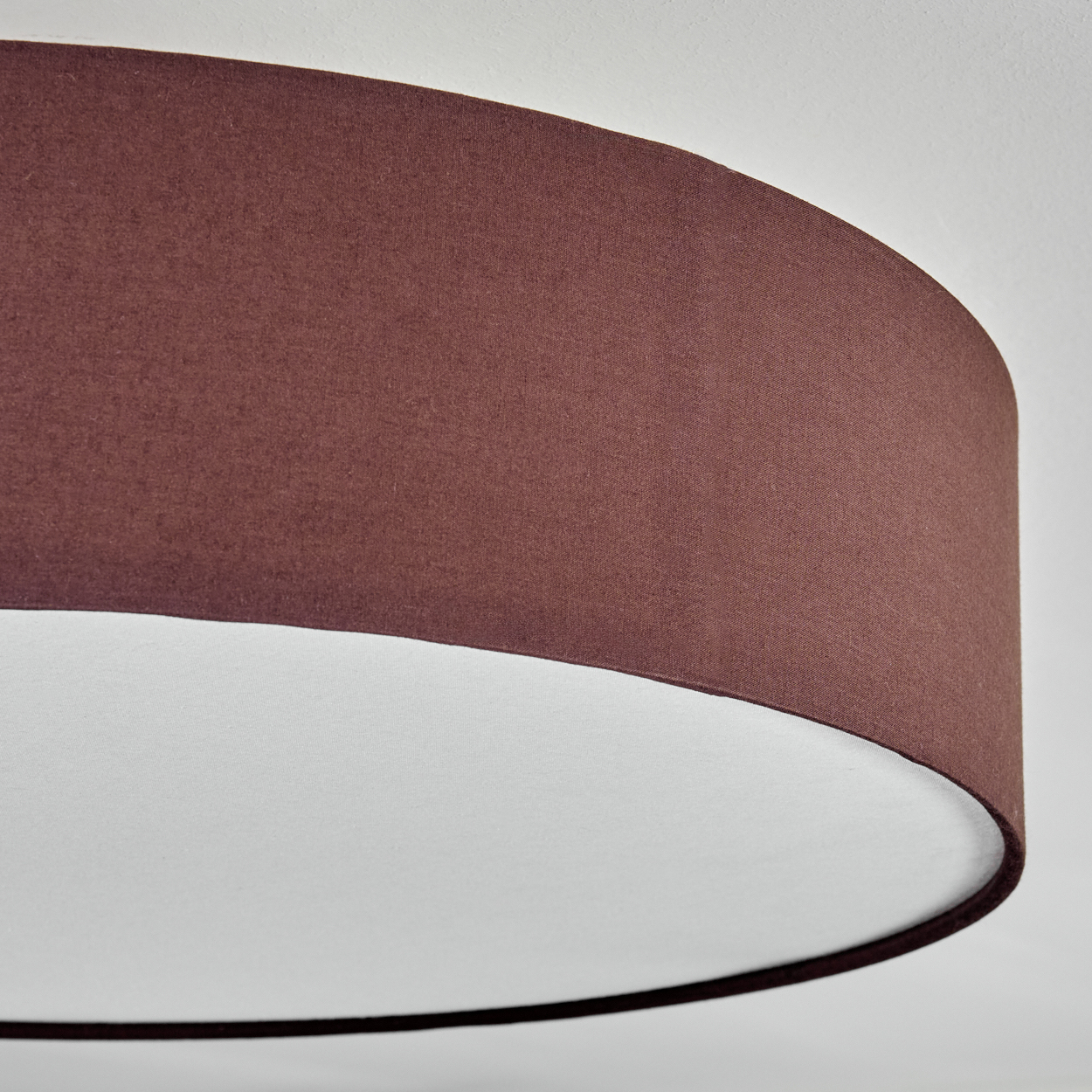 Nahaufnahme eines Lampenschirms. Er ist außen dunkelbraun und innen weiß. Der Hintergrund ist weiß.