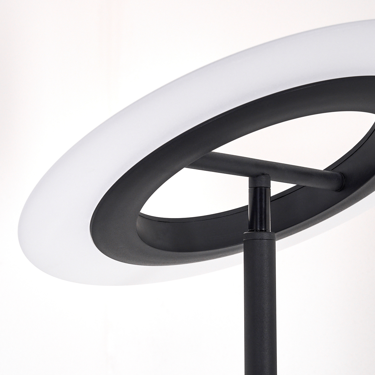 Eine moderne schwarze Lampe mit einem kreisförmigen, weiß beleuchteten Oberteil. Der Sockel ist eine schwarze Stange. Der Hintergrund ist weiß.