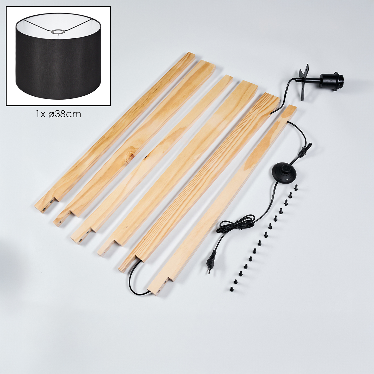 Eine zerlegte Lampe. Zu den Komponenten gehören Holzlatten, ein schwarzer Lampenschirm, eine Leuchte und Schrauben auf weißem Grund.
