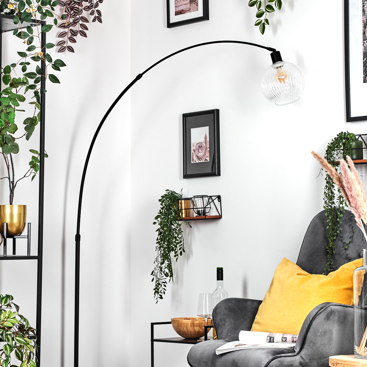 Ein modernes Wohnzimmer mit einer schwarzen Bogenlampe, einem grauen Sessel mit gelbem Kissen und Pflanzen in stilvollem Interieur.