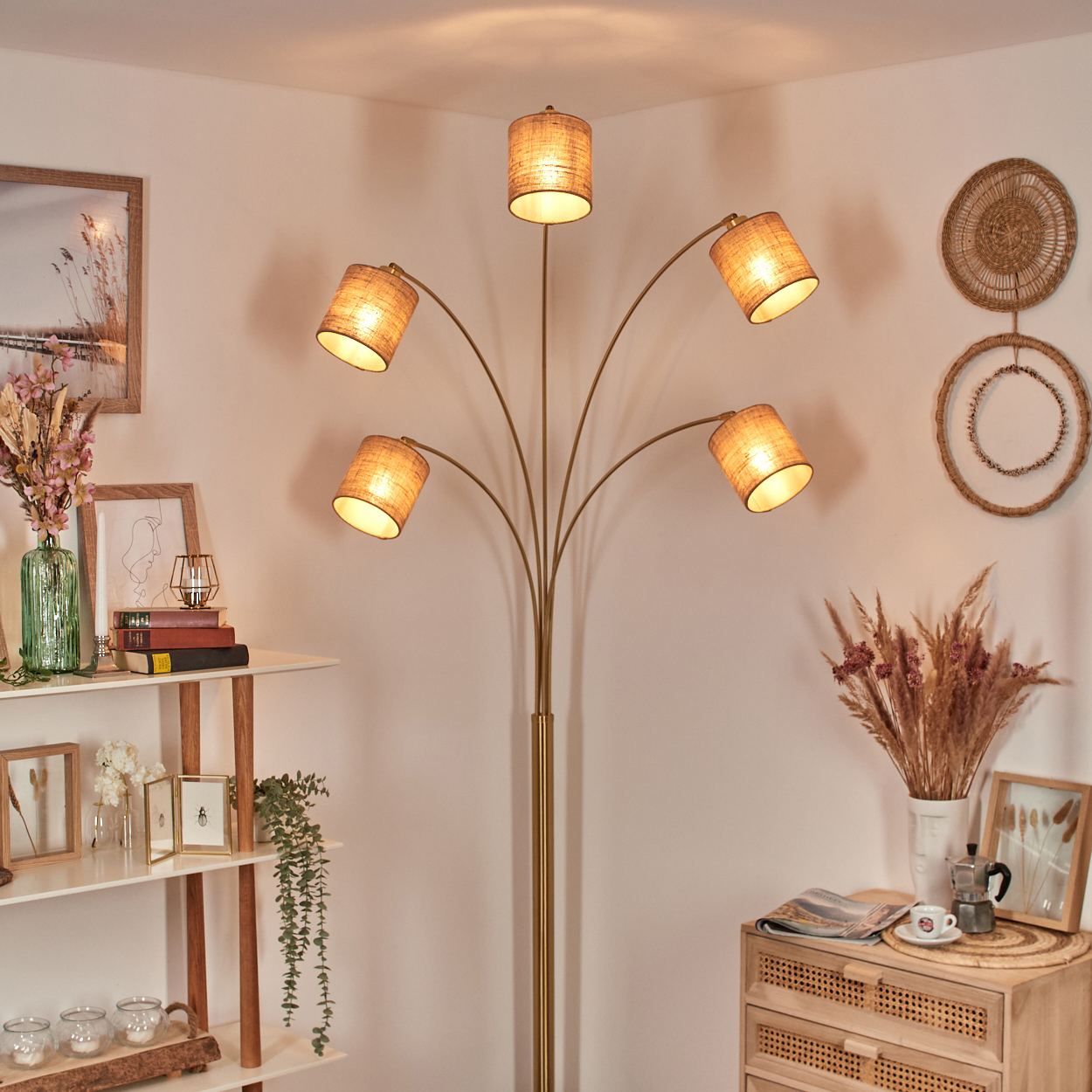 Eine Stehlampe mit fünf Schirmen beleuchtet einen Raum mit Regal, Kommode und Dekoration.