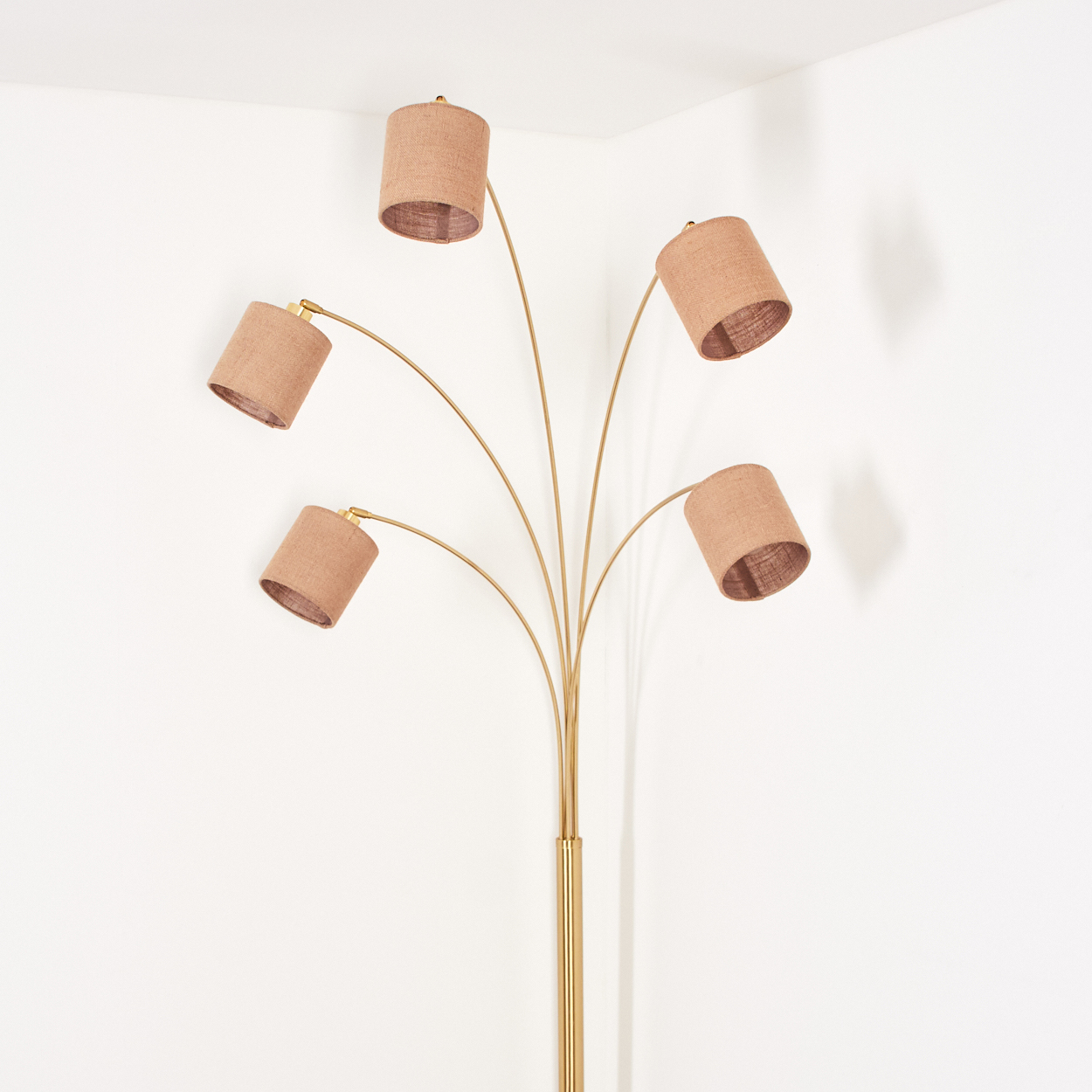 Eine goldene Stehlampe mit fünf Schirmen. Die Schirme sind beige, der Hintergrund ist weiß.