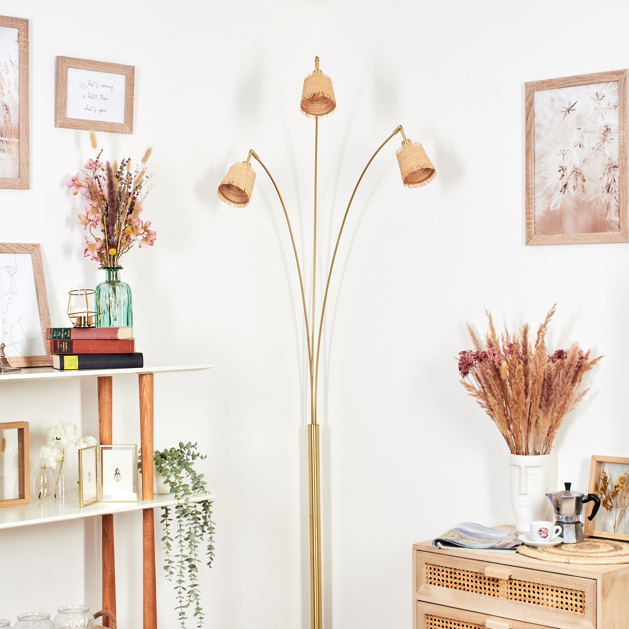Ein Raum mit Stehlampe, Regalen mit Dekoration und einem Holzschrank. Es gibt Blumengestecke und gerahmte Bilder.