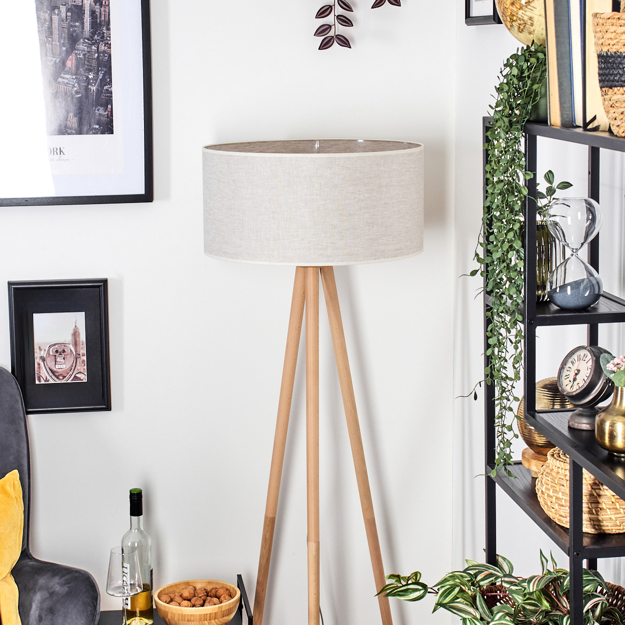 Ein Raum mit einer Holzlampe, einem schwarzen Regal mit Dekorationen und gerahmten Bildern an einer weißen Wand.