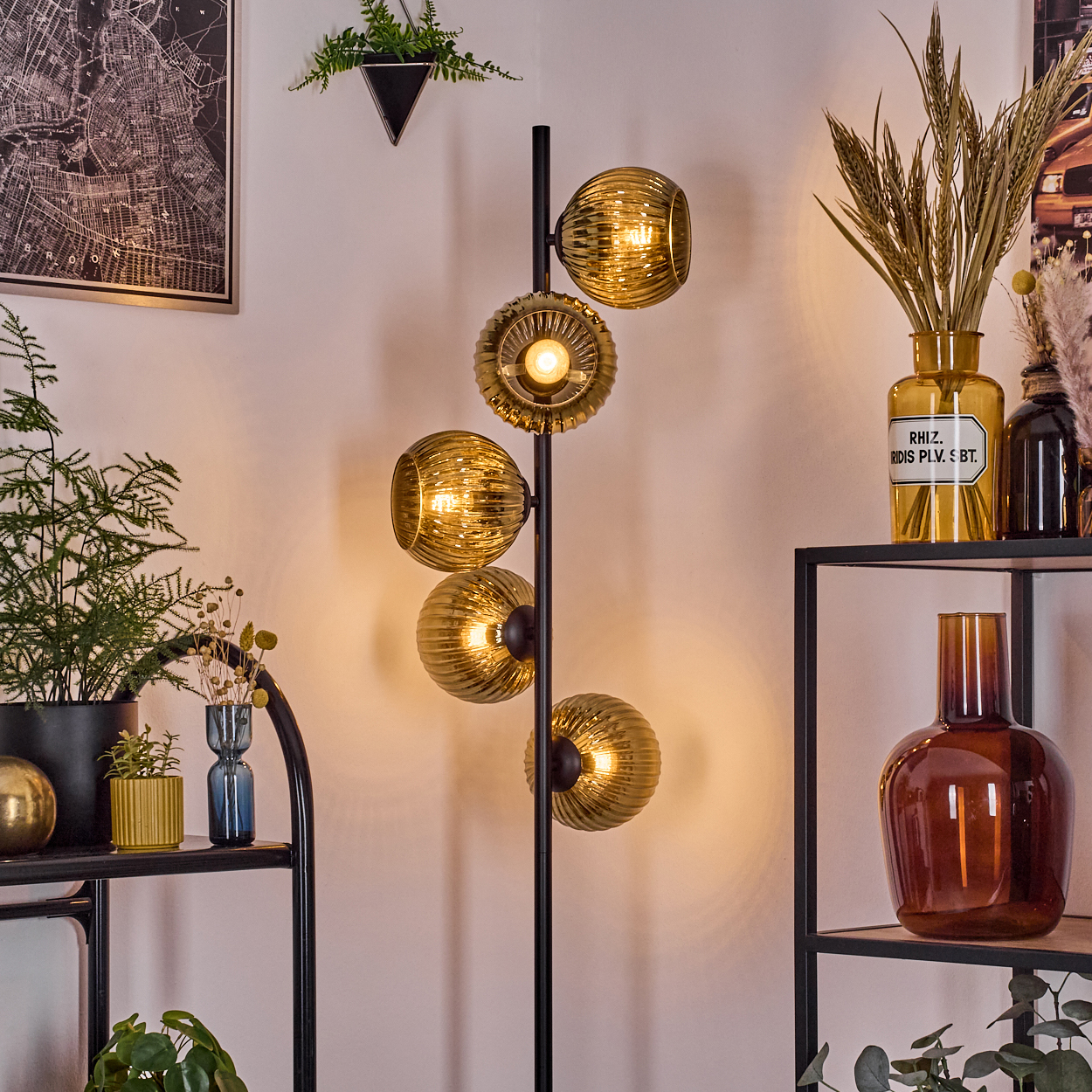 Ein modernes Wohnzimmer mit einer schwarzen Stehlampe mit Glasschirmen, Regalen, Pflanzen und Dekorationsgegenständen. Warme Beleuchtung.