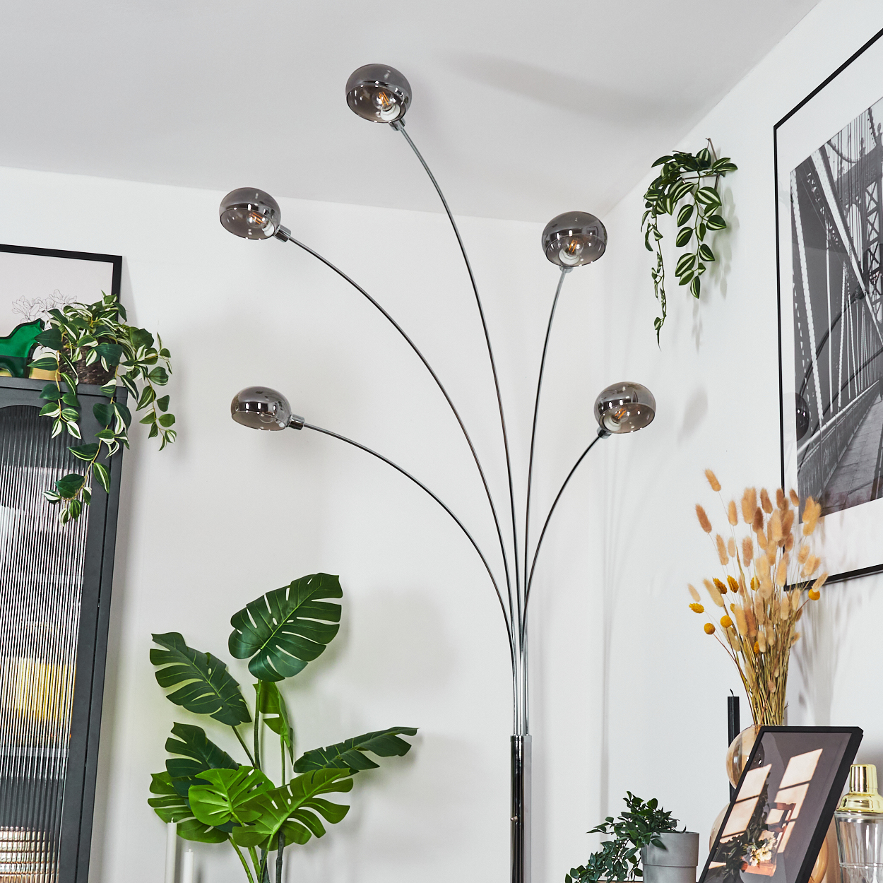 Eine moderne Stehlampe mit fünf Glaskugeln. Pflanzen und gerahmte Kunst schmücken den Raum. Ein stilvolles Interior Design.