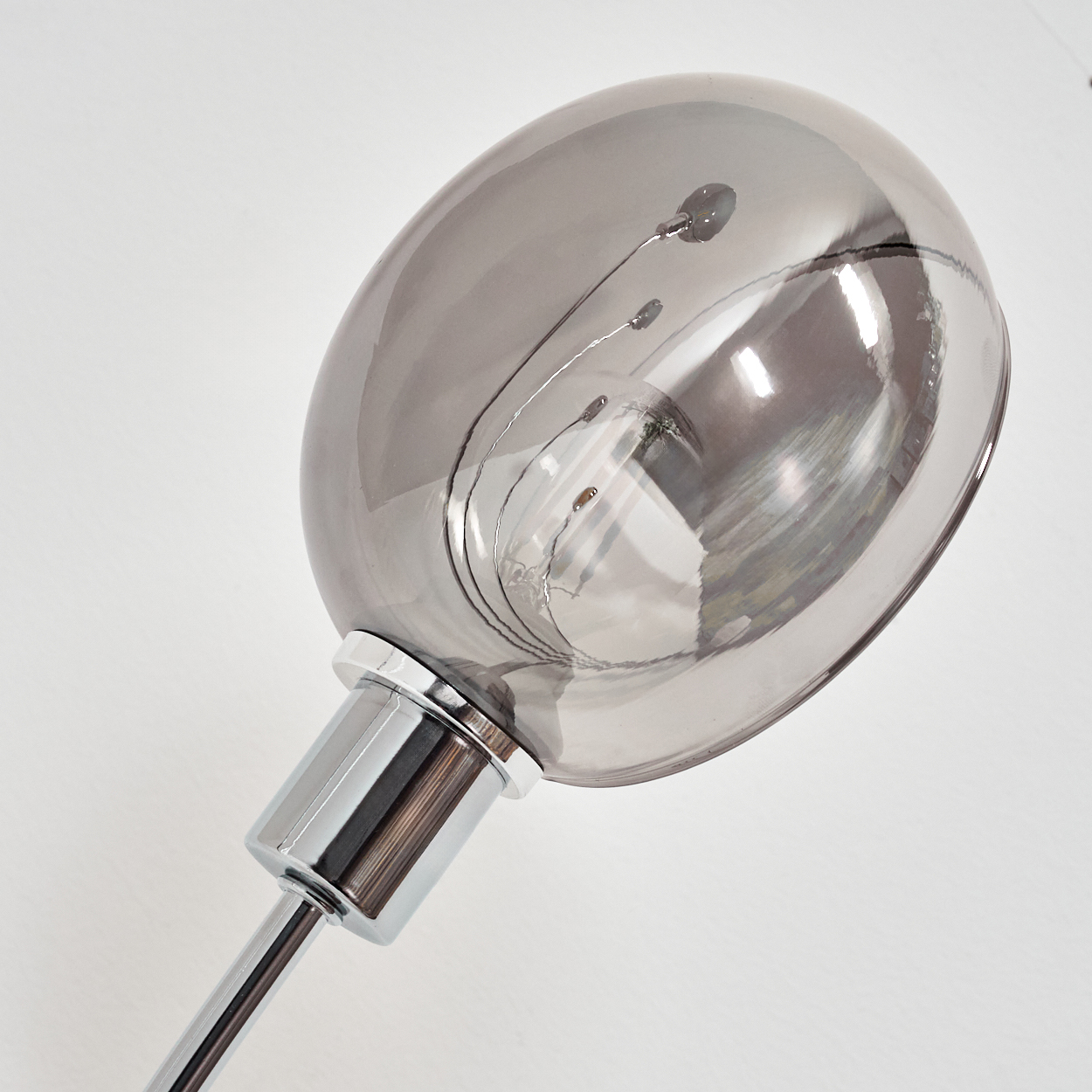 Eine moderne Lampe mit einem großen, grauen, ovalen Schirm. Der Fuß ist verchromt, der Hintergrund ist weiß.