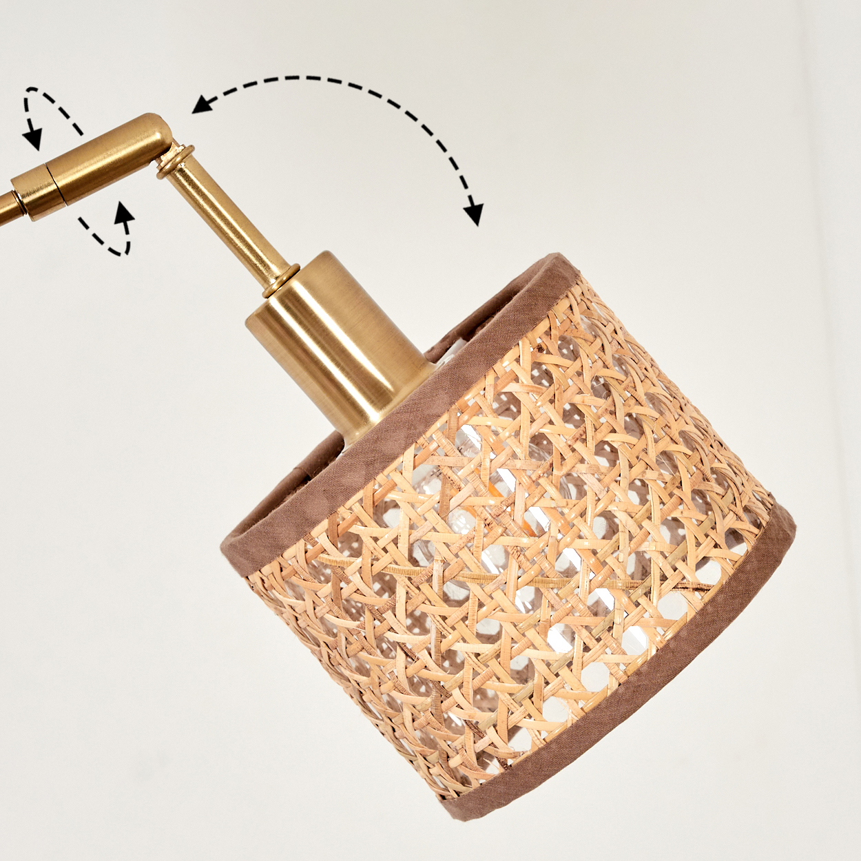 Nahaufnahme einer Lampe mit gewebtem Schirm. Die Lampe hat einen goldfarbenen Arm und einen braunen Stoffrand um den Schirm.
