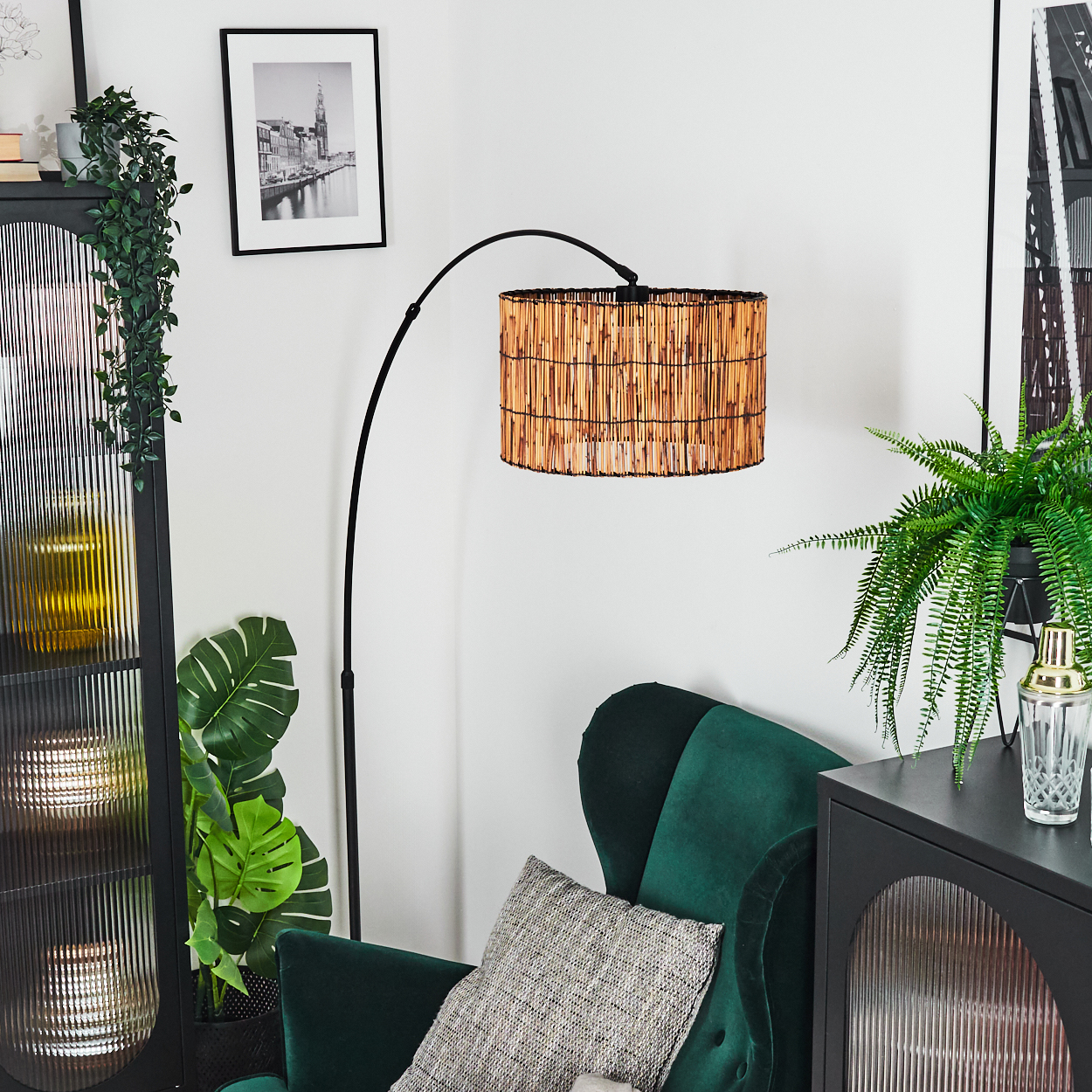 Wohnzimmerszene mit grünem Sessel, Lampe mit gewebtem Lampenschirm und schwarzem Schrank mit Pflanzen.