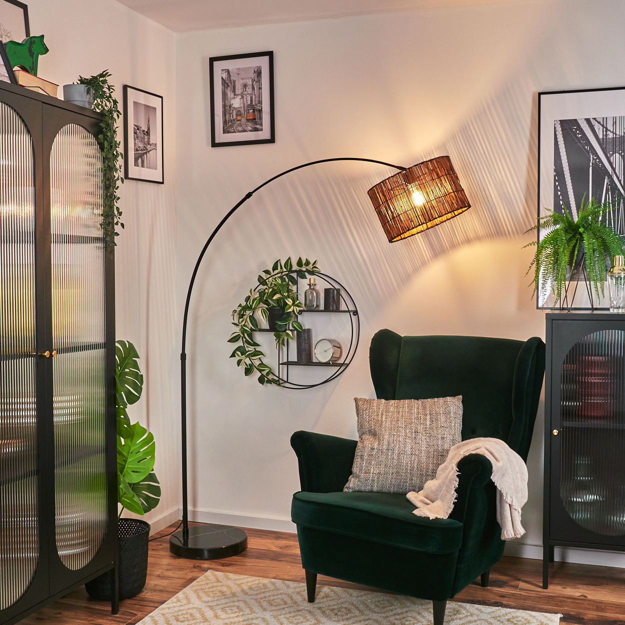 Ein dunkelgrüner Sessel mit Kissen und Decke, eine schwarze Stehlampe und ein Schrank in einem Wohnzimmer.