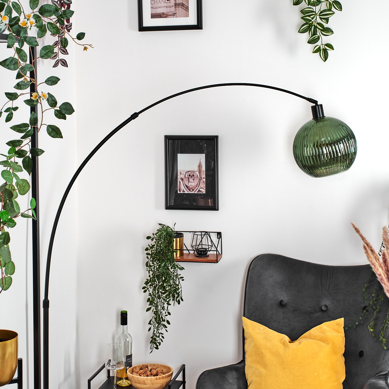 Ein modernes Wohnzimmer mit einer schwarzen Stehlampe, einem grünen Lampenschirm, einem grauen Sessel und einem gelben Kissen.