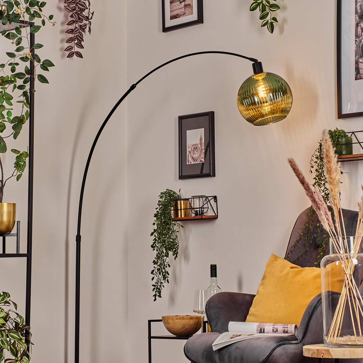 Ein modernes Wohnzimmer mit einer schwarzen Bogenlampe, einem grauen Sessel und dekorativen Pflanzen. Auf dem Stuhl liegt ein gelbes Kissen.