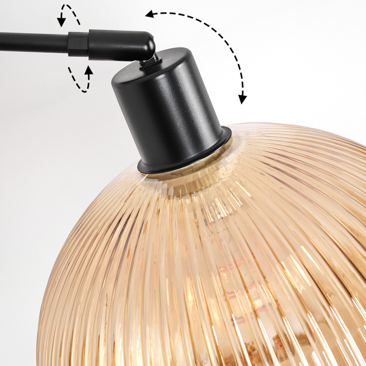 Nahaufnahme einer Lampe. Sie hat einen schwarzen Arm und einen golden gerippten Glasschirm. Pfeile zeigen die Verstellbarkeit.