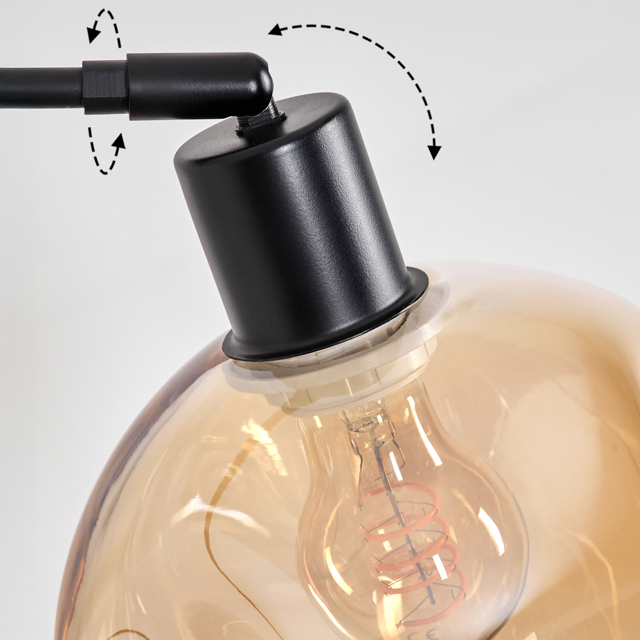 Nahaufnahme einer schwarzen Lampe mit einer klaren, hellbraunen Glühbirne. Der Glühfaden der Glühbirne ist sichtbar. Gestrichelte Pfeile zeigen verstellbare Teile an.