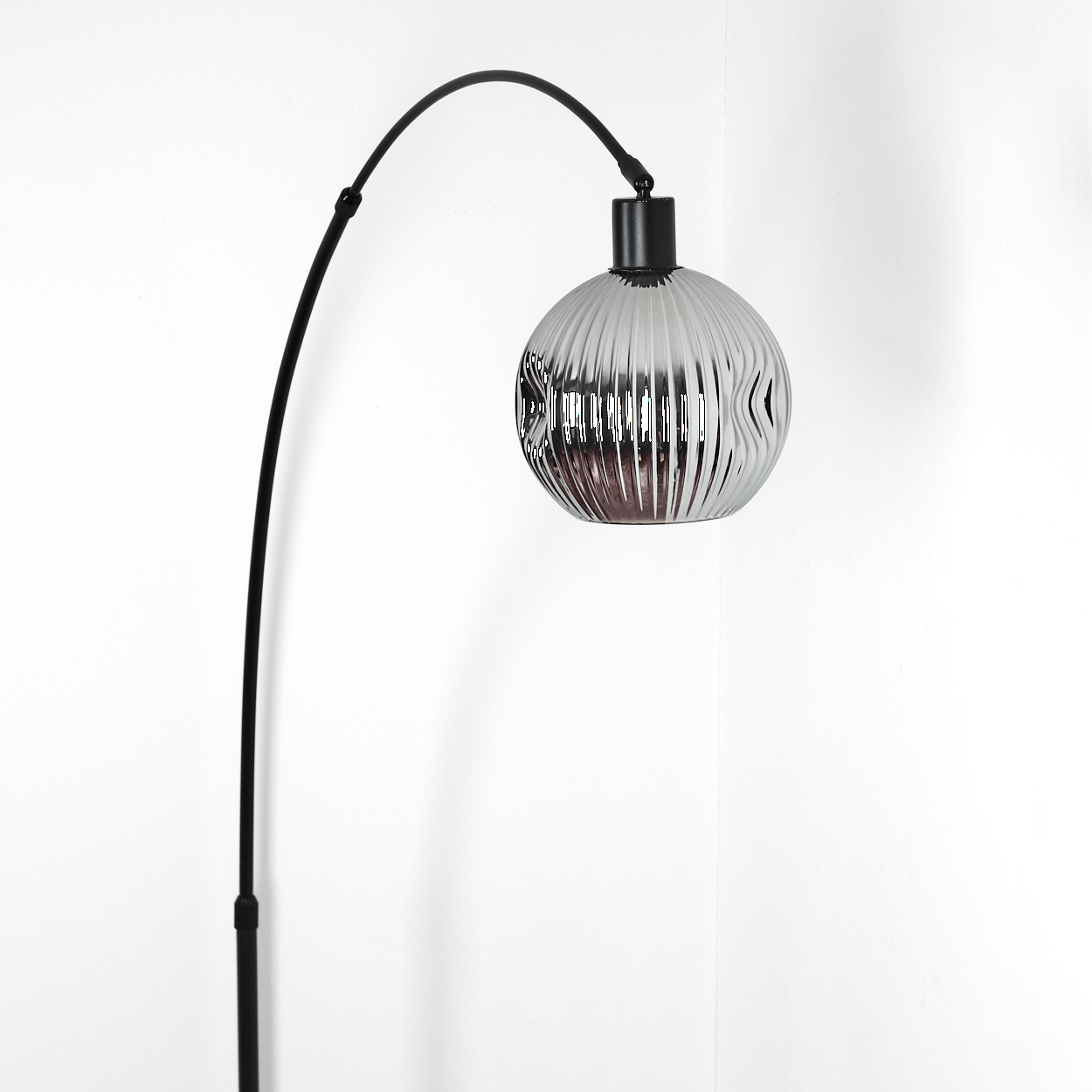 Eine moderne schwarze Lampe mit gebogenem Arm hält einen kugelförmigen, gerippten Glasschirm. Der Hintergrund ist eine weiße Wand.