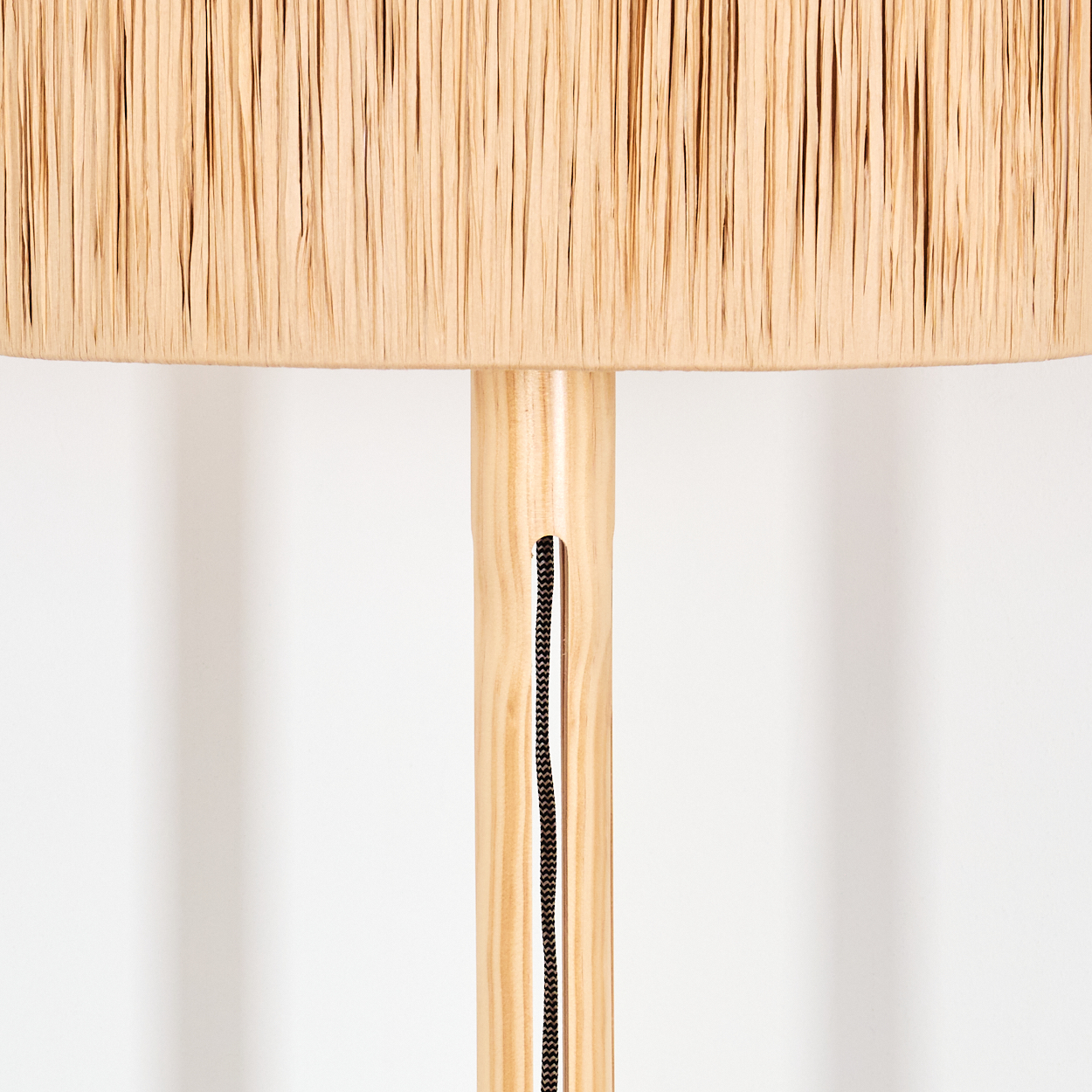 Nahaufnahme einer Lampe. Der Lampenschirm ist beige, der Holzkörper hellbraun und ein schwarzes Kabel verläuft daran.