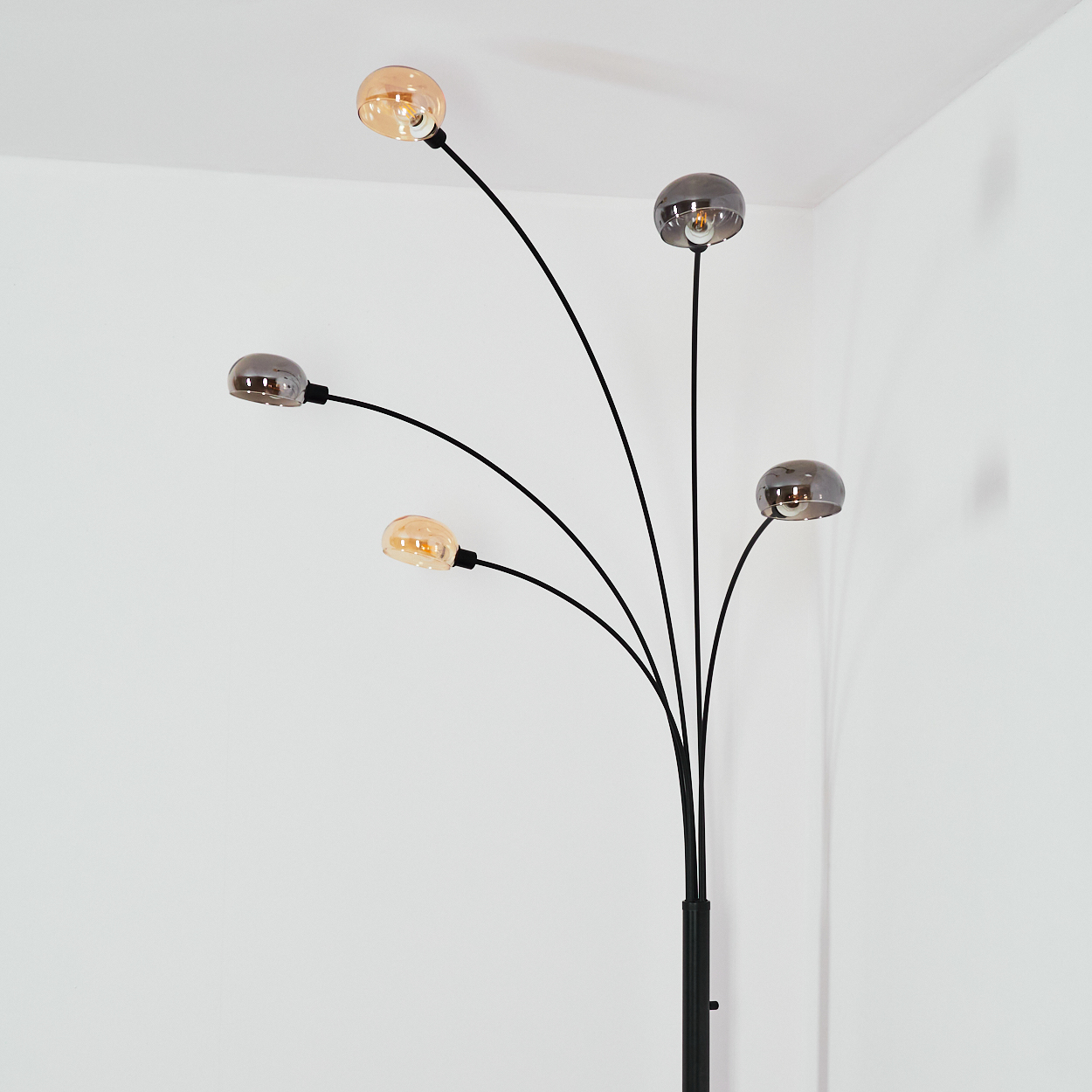 Eine moderne Stehlampe mit fünf Glühbirnen. Die Birnen sind rund und haben unterschiedliche Farben. Die Lampe ist schwarz, der Hintergrund weiß.
