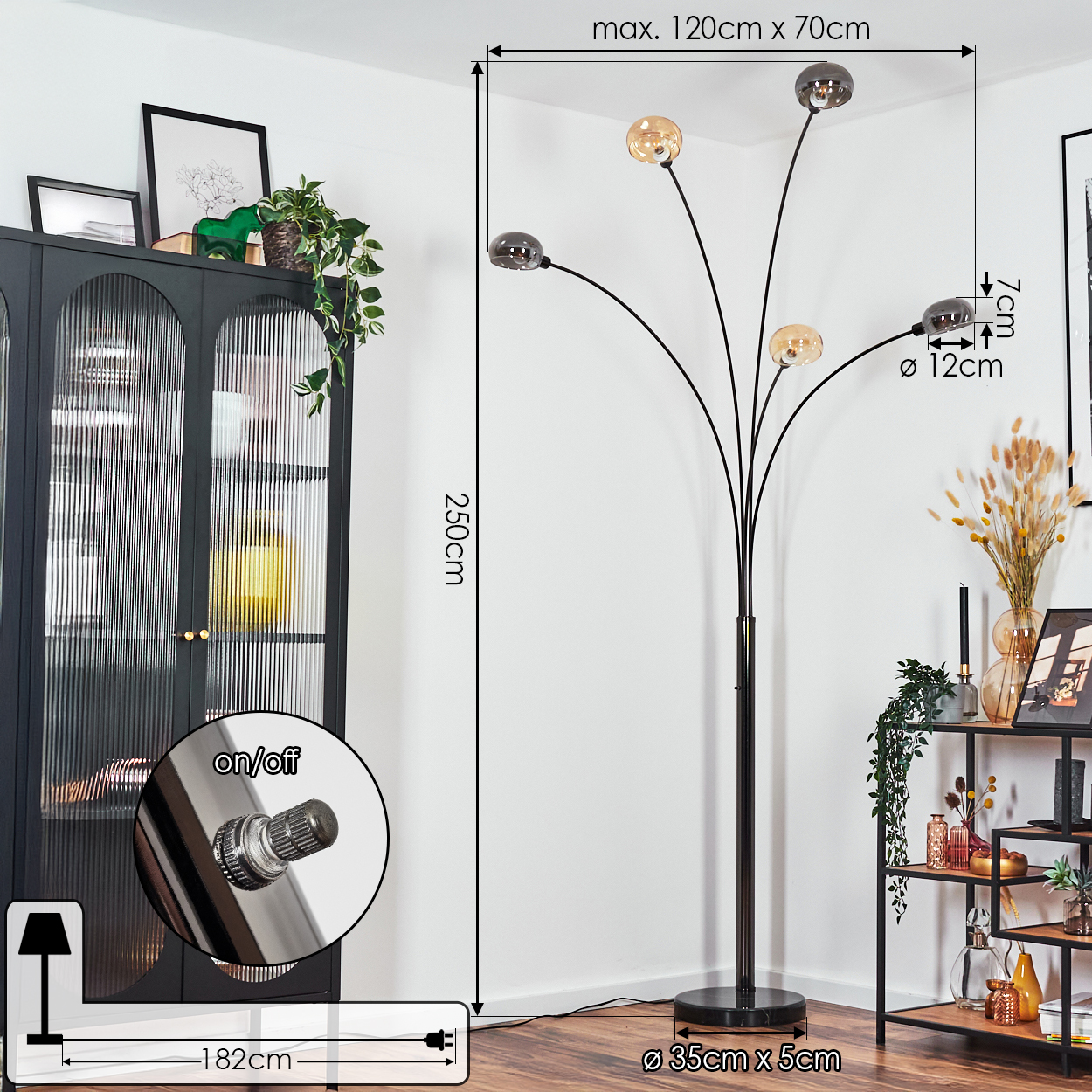 Eine Stehlampe mit fünf Lichtern. Sie ist schwarz und hat beschriftete Abmessungen. Links ein Schrank, rechts ein Regal.