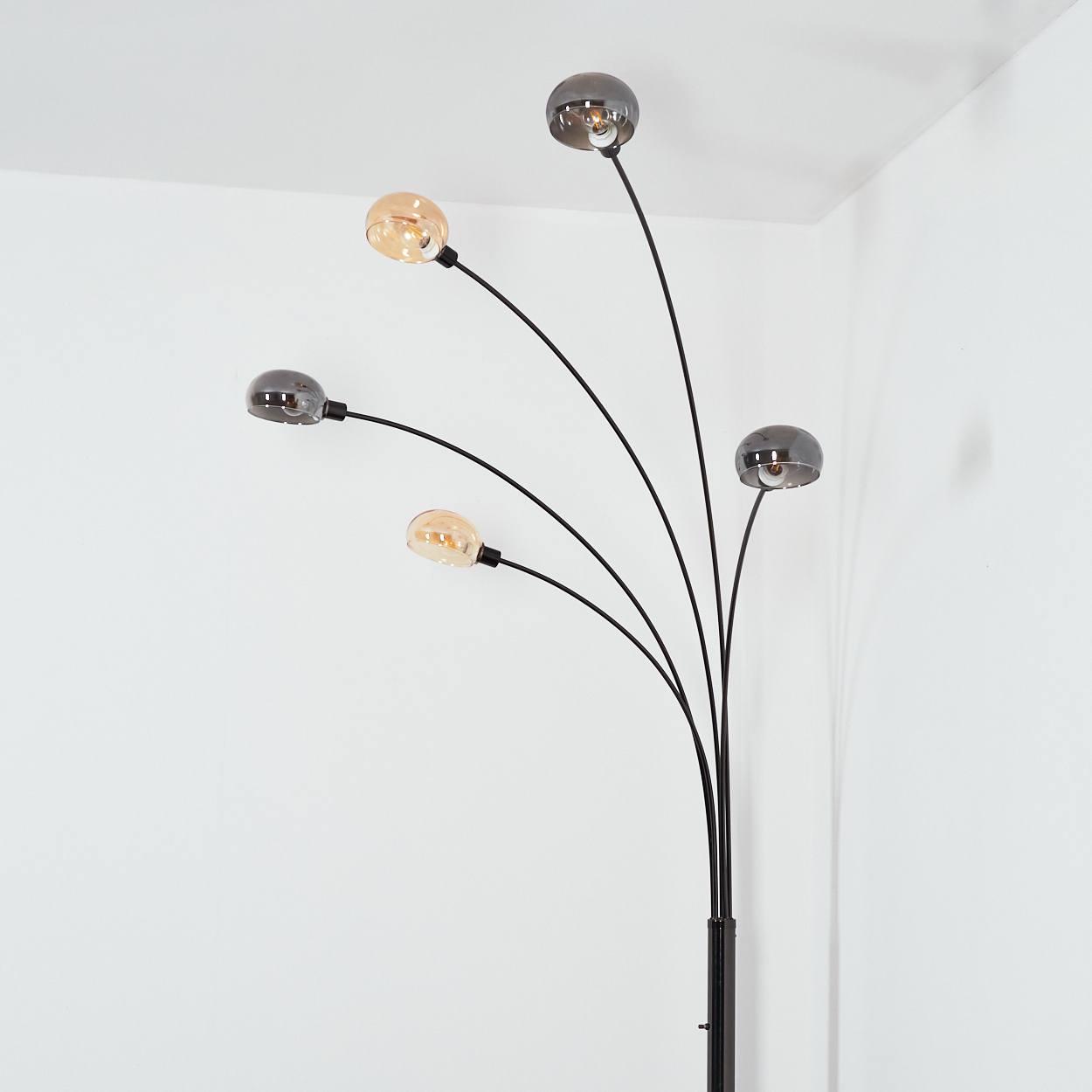 Eine moderne Stehlampe mit fünf gebogenen Armen, die jeweils eine runde Leuchte halten. Einige sind bernsteinfarben, andere Rauchglas, mit einem schwarzen Stiel.