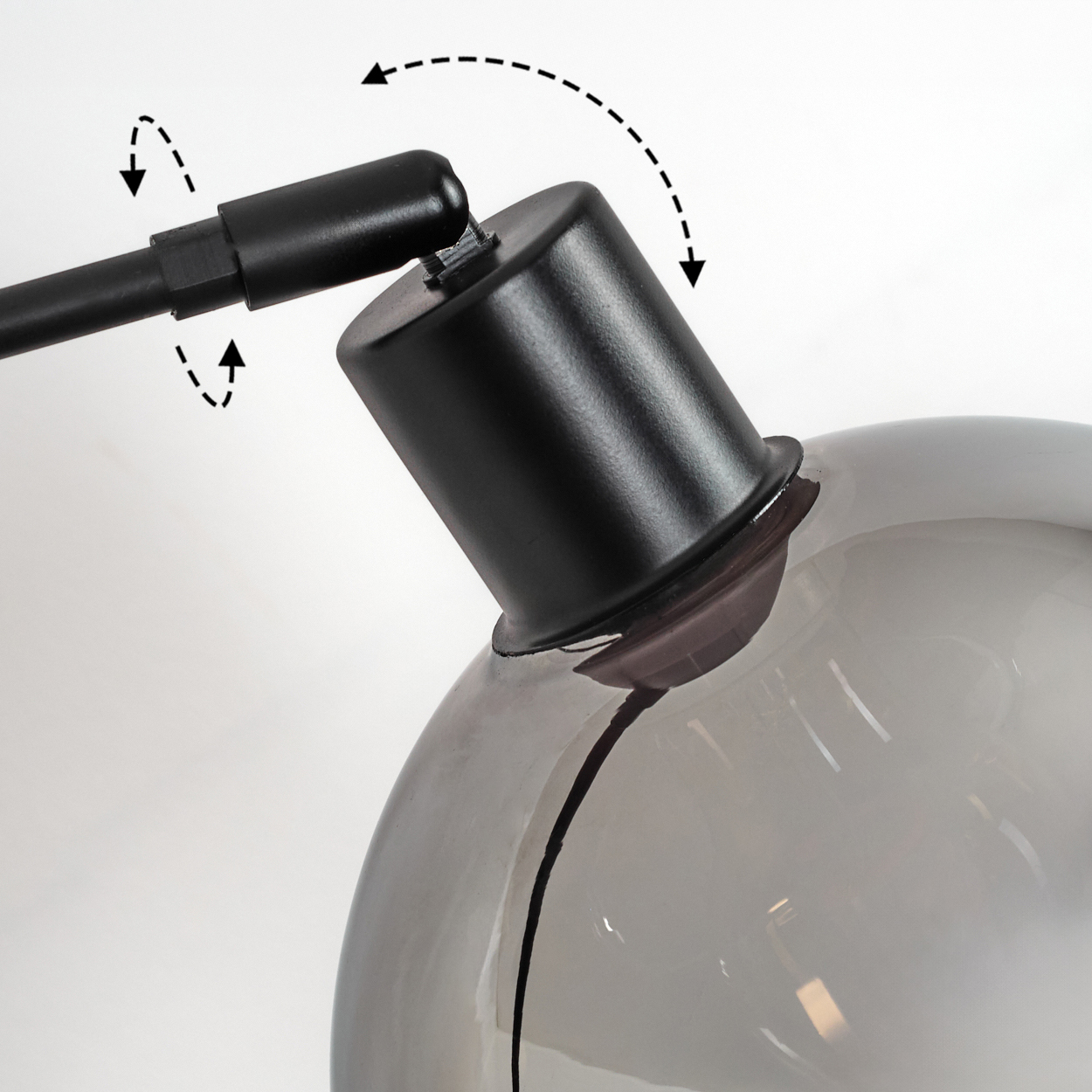 Nahaufnahme einer Lampe mit schwarzem Arm und Schirm. Der Schirm ist eine transparente Kugel. Pfeile zeigen die Verstellbarkeit an.