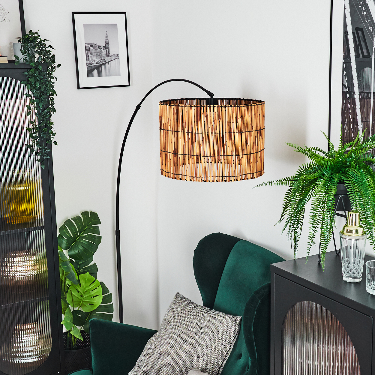 Eine Zimmerecke mit grünem Sessel, Lampe mit Korbschatten und schwarzem Schrank mit Pflanzen.