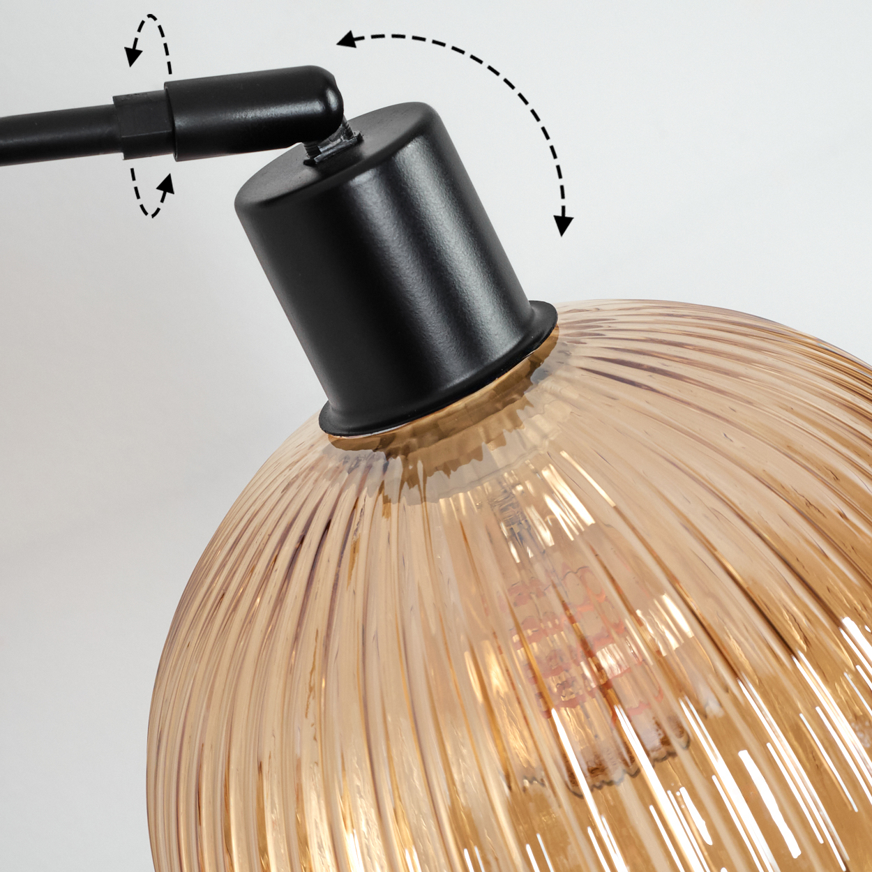 Nahaufnahme einer schwarzen Lampe mit bernsteinfarbenem Glasschirm. Pfeile zeigen verstellbare Teile. Der Hintergrund ist weiß.
