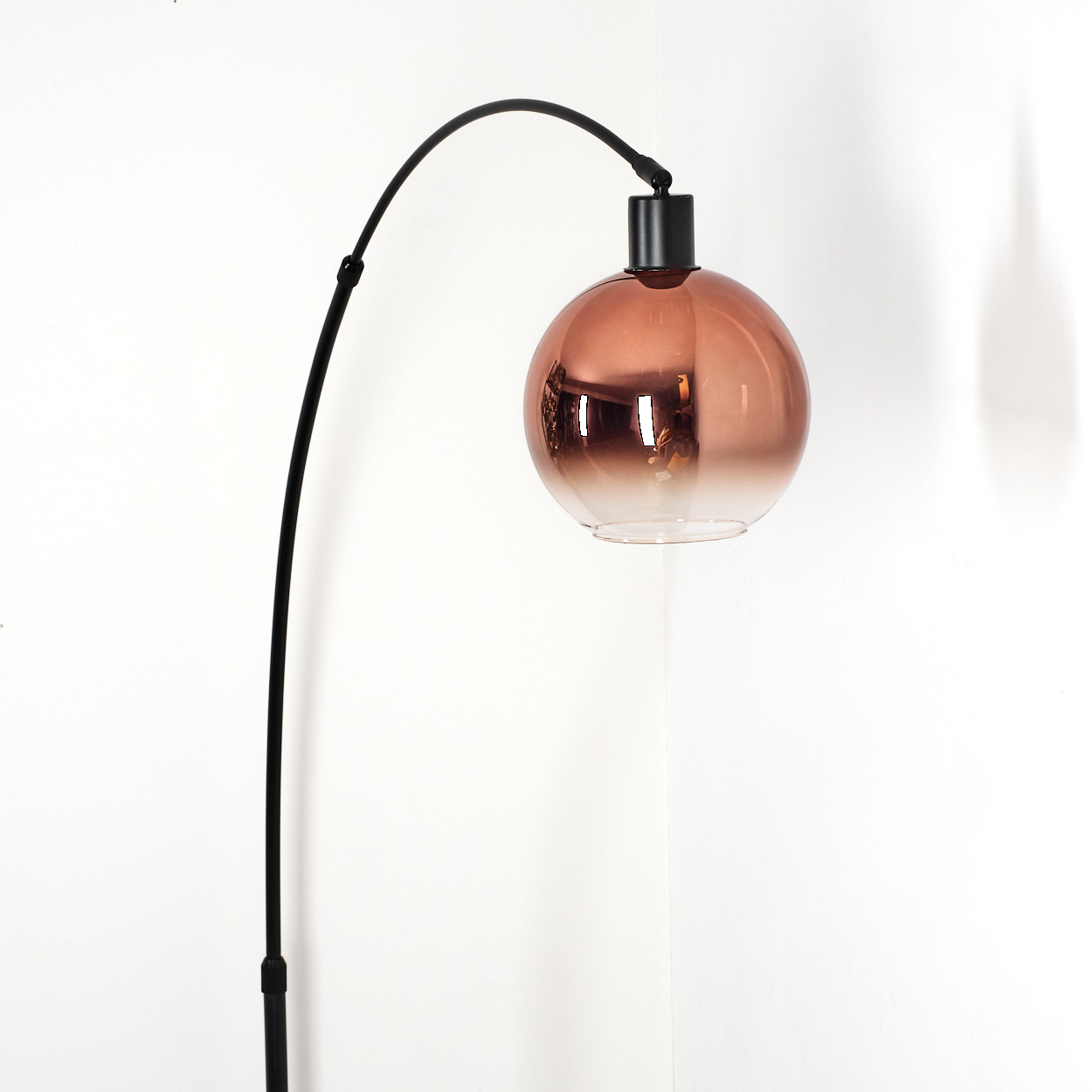 Eine moderne Stehlampe mit gebogenem schwarzem Stiel und einem runden, farbverlaufenden Lampenschirm, der von Braun zu Klar übergeht.