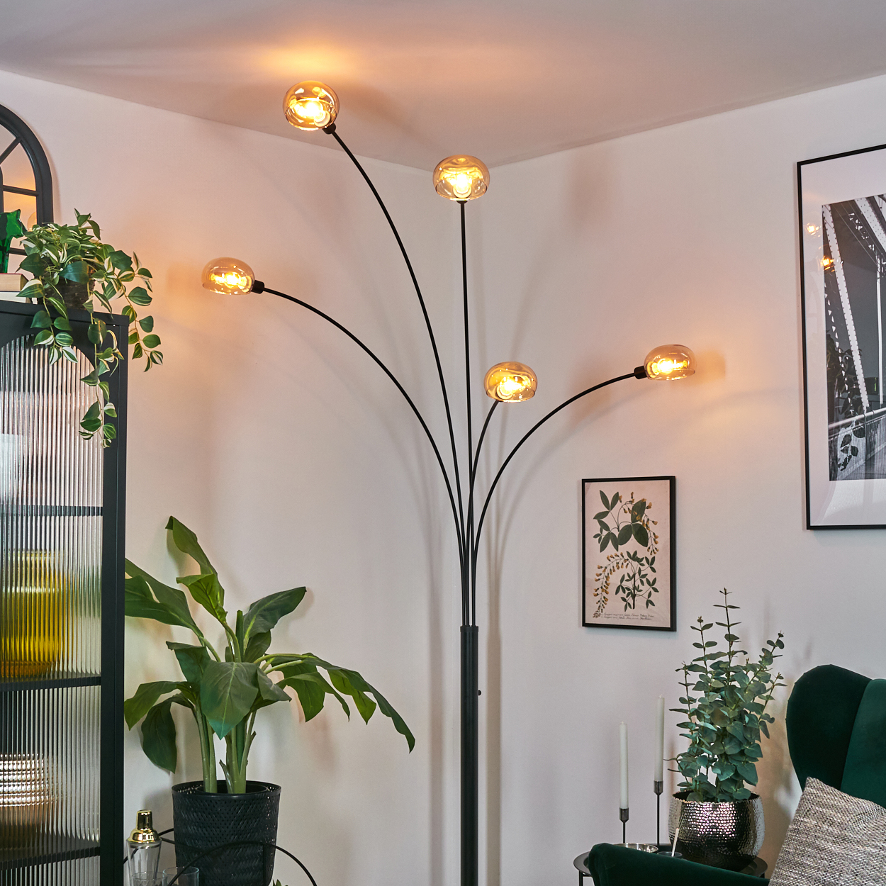 Ein modernes Wohnzimmer mit einer schwarzen Bogenlampe mit fünf Kugelleuchten. Pflanzen und Kunstwerke sind ebenfalls vorhanden.