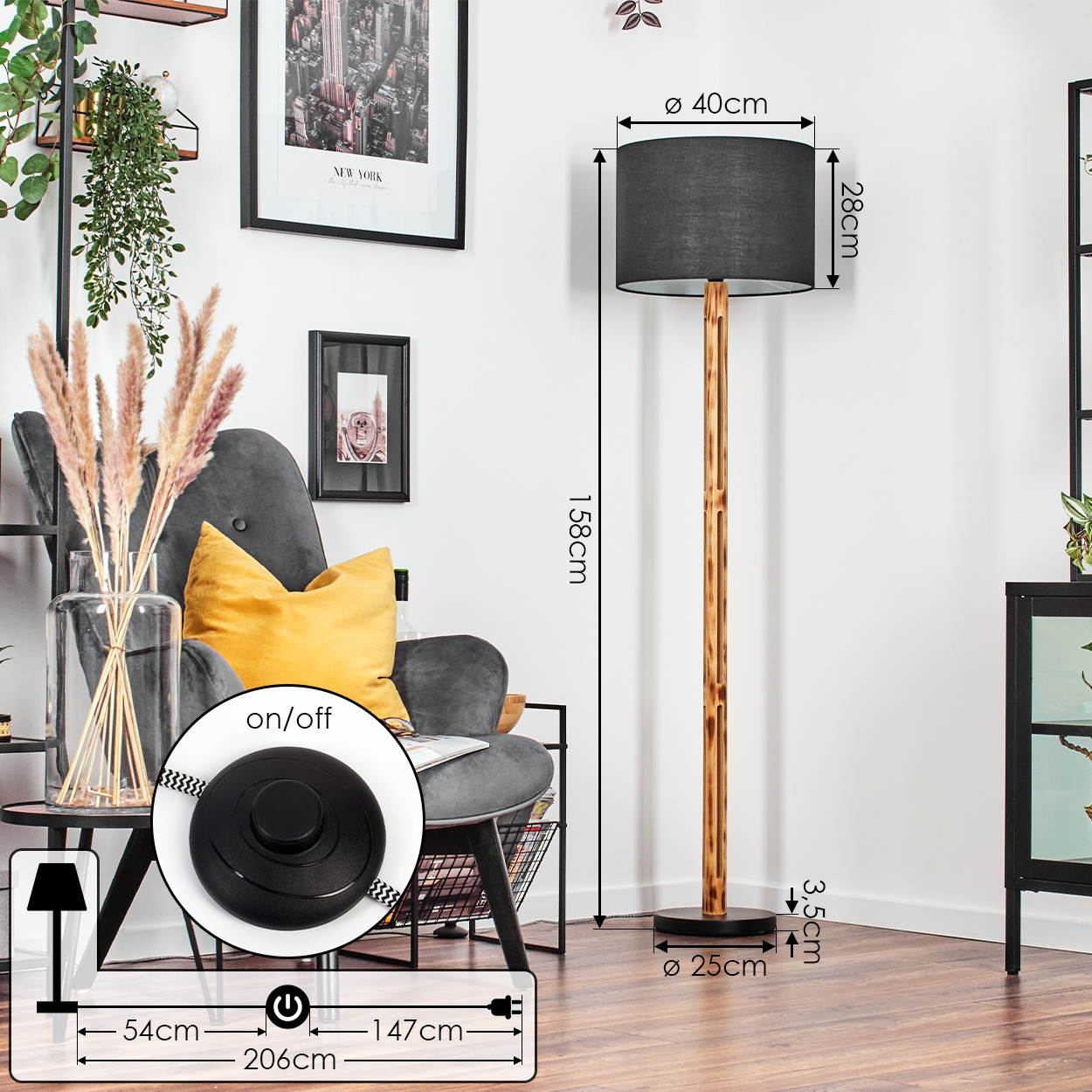 Ein Raum mit einer Stehlampe. Die Lampe hat einen schwarzen Lampenschirm und einen Holzfuß. Es gibt einen grauen Sessel und ein Gemälde an der Wand.