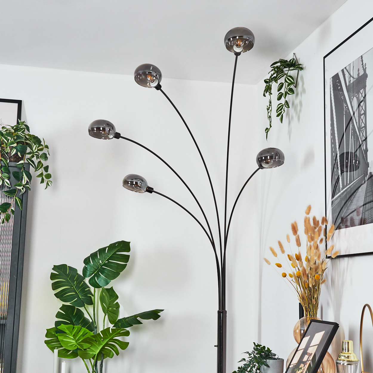 Eine moderne Stehlampe mit fünf kugelförmigen Leuchten. Pflanzen und gerahmte Kunst schmücken den Raum.