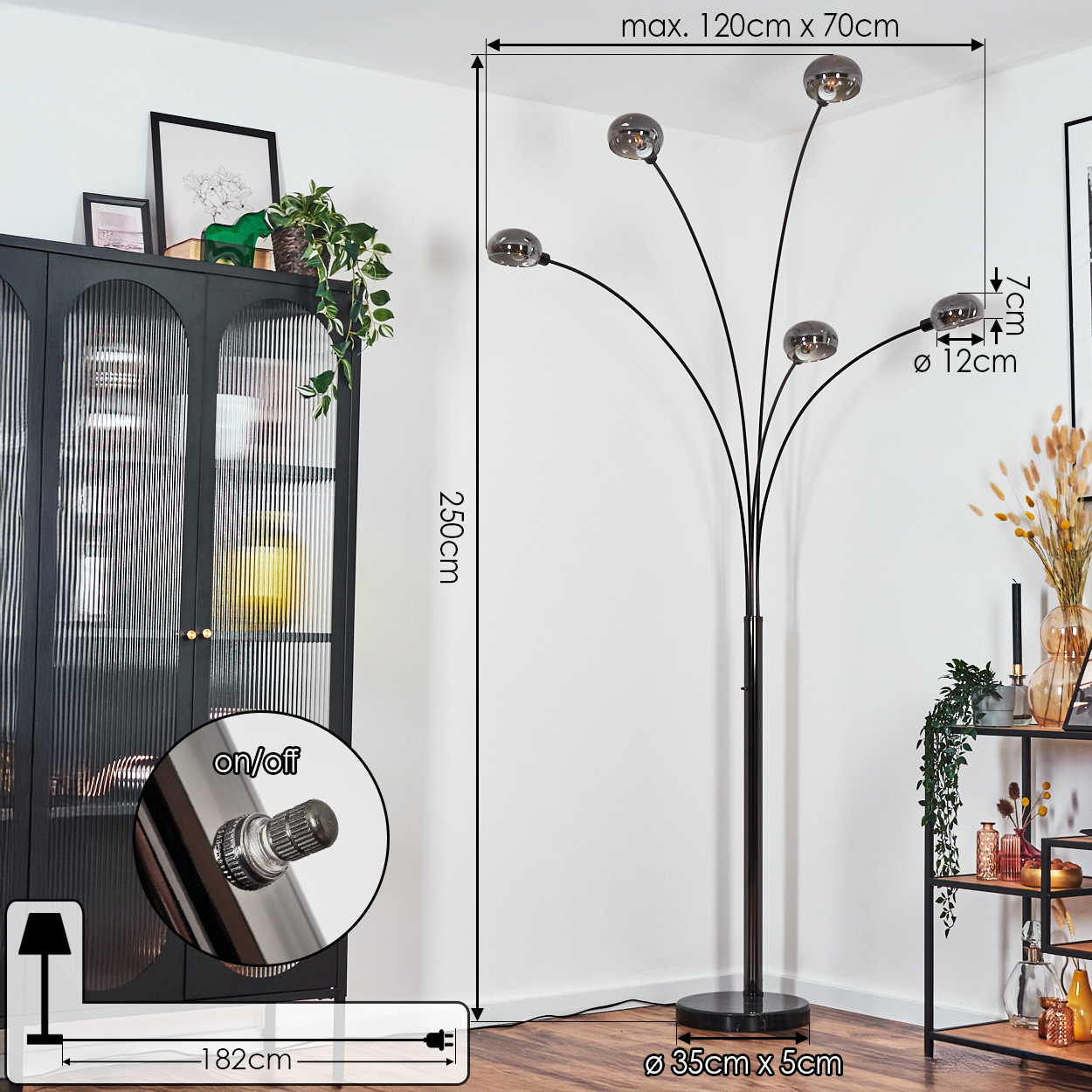 Eine schwarze Stehlampe mit fünf kugelförmigen Lichtern steht in einem Raum. Ein schwarzer Schrank und ein schwarzes Regal sind ebenfalls vorhanden.