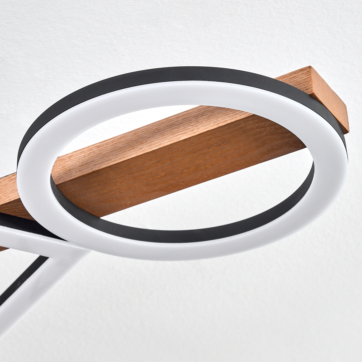 Eine moderne Lampe mit kreisförmigem Licht und einem Holzbalken. Das Licht ist weiß, von Schwarz umrandet. Der Hintergrund ist weiß.