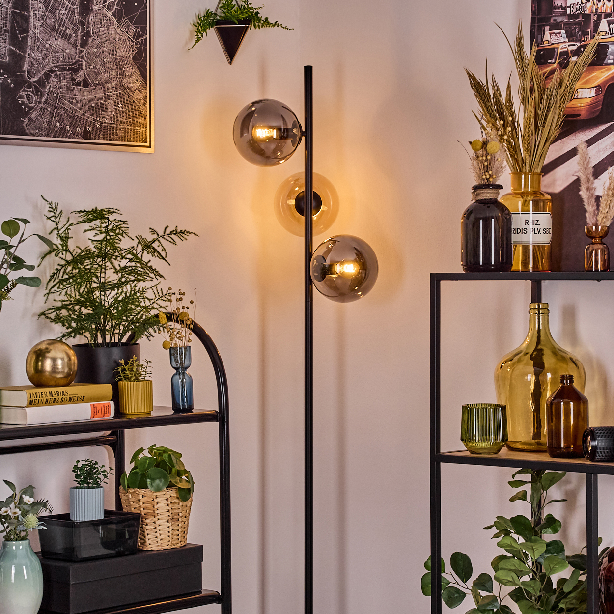 Raumecke mit Stehlampe. Regale mit Pflanzen, Büchern, Vasen und Dekorationsartikeln. Karte und Kunstwerk an der Wand.