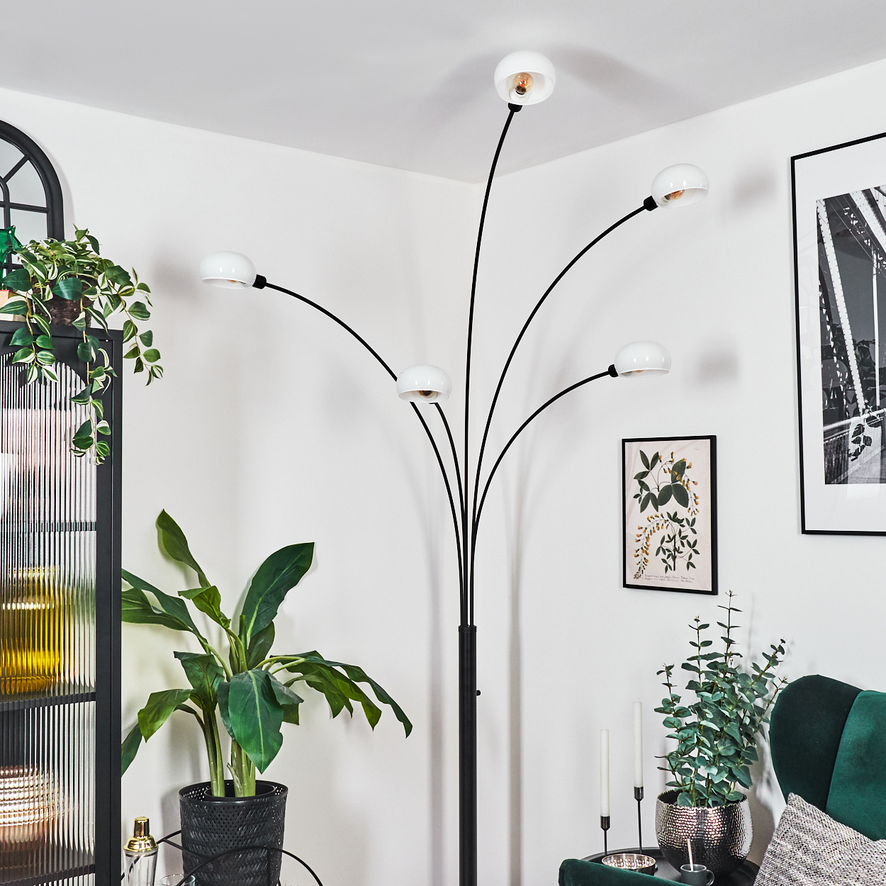 Ein modernes Wohnzimmer mit schwarzer Stehlampe, Pflanzen, Bild, grünem Sessel und schwarzem Schrank.
