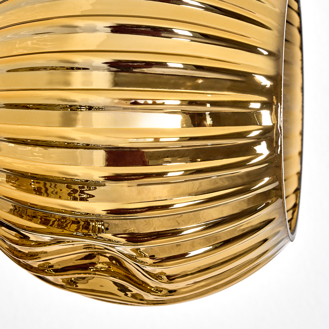 Nahaufnahme eines goldenen, gerippten, gebogenen Objekts vor weißem Hintergrund. Das Objekt ist stark reflektierend und glänzend.