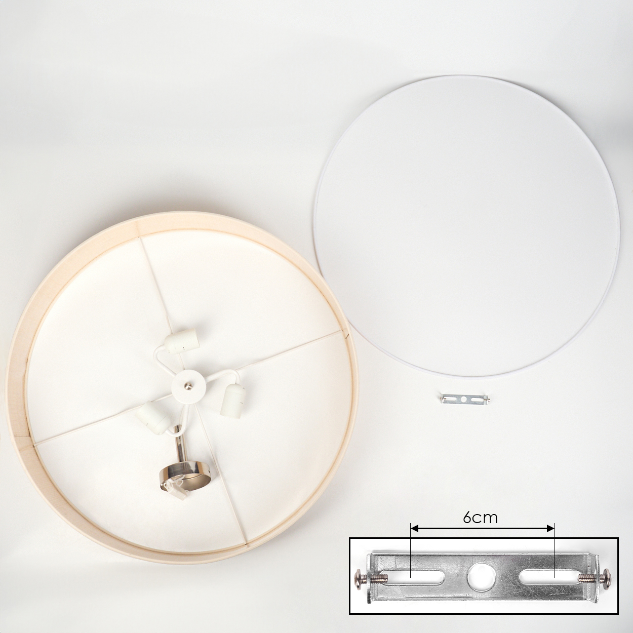 Draufsicht einer zerlegten Lampe. Komponenten: Lampenschirm, weißer Metallkreis und Metallhalterung mit 6 cm Messung.