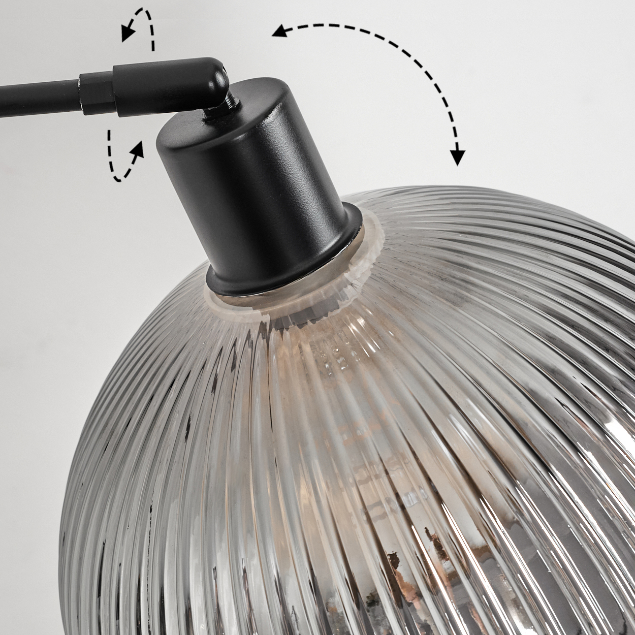 Nahaufnahme einer schwarzen Lampe mit geripptem, klarem Glasschirm. Pfeile zeigen verstellbare Positionen. Weißer Hintergrund.