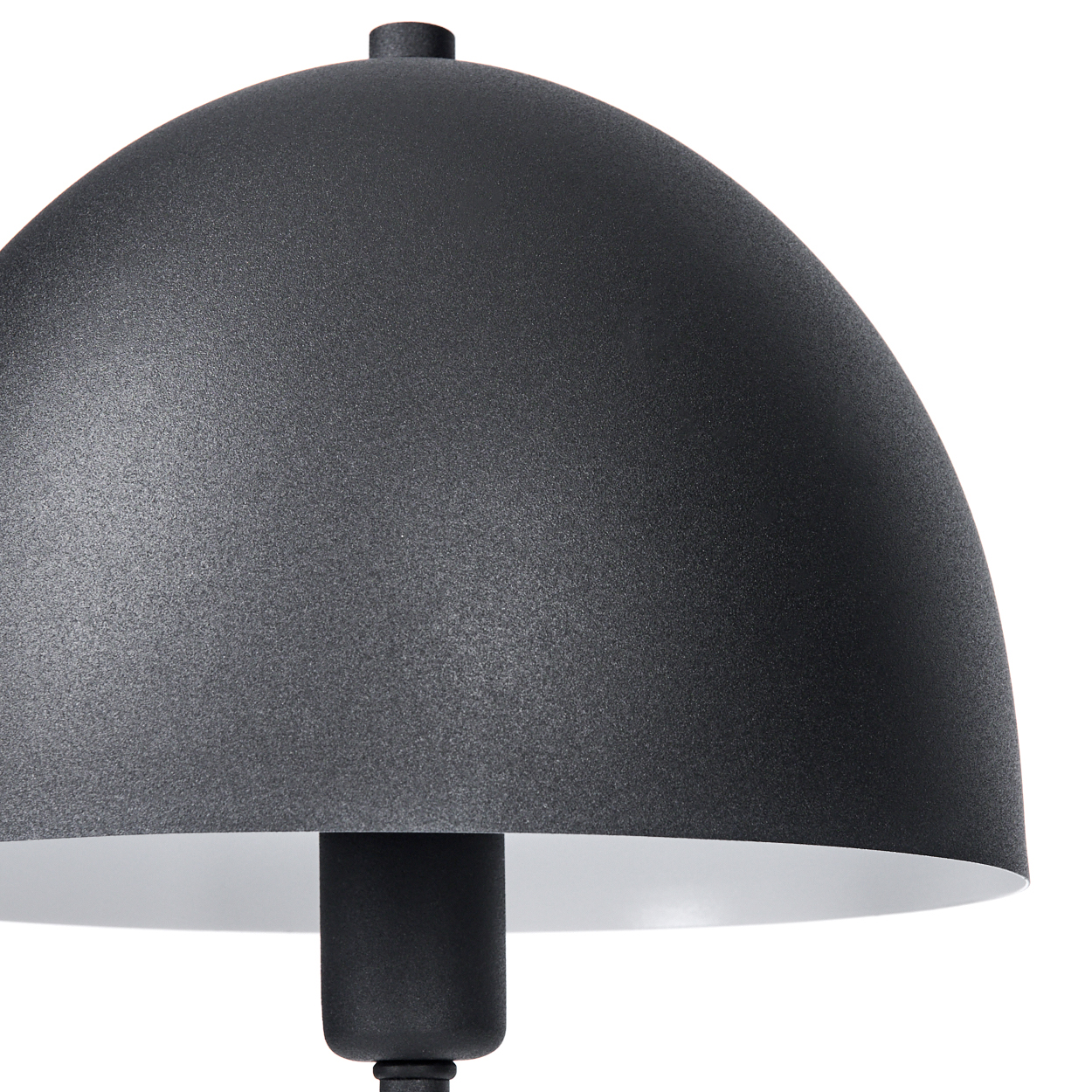 Nahaufnahme einer schwarzen Lampe. Der Lampenschirm ist kuppelförmig mit strukturierter Oberfläche und weißem Innenraum. Der Stiel ist schwarz.