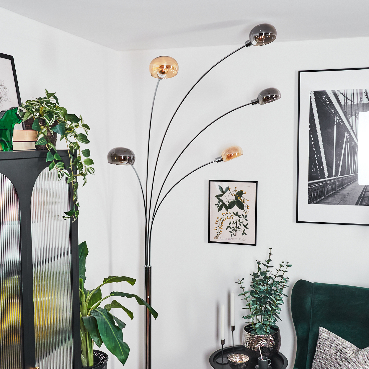 Ein modernes Wohnzimmer mit Stehlampe, Pflanzen, Kunstwerken und einem grünen Sessel, das eine stilvolle und gemütliche Atmosphäre schafft.