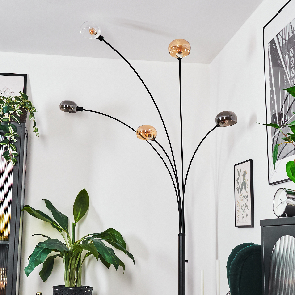 Eine moderne Stehlampe mit fünf kugelförmigen Lichtern. Der Raum umfasst Pflanzen, Kunstwerke und Möbel vor weißen Wänden.