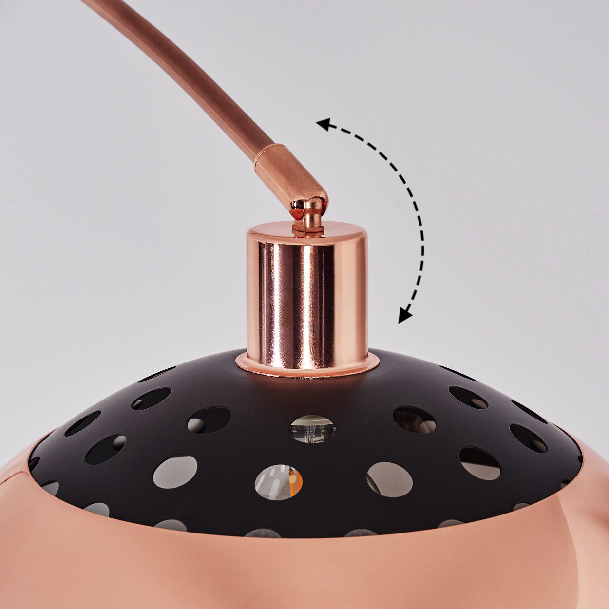 Nahaufnahme einer kupfer-schwarzen Lampe. Die Lampe hat einen perforierten schwarzen Schirm und einen kupferfarbenen Arm. Ein Pfeil zeigt die Bewegung an.