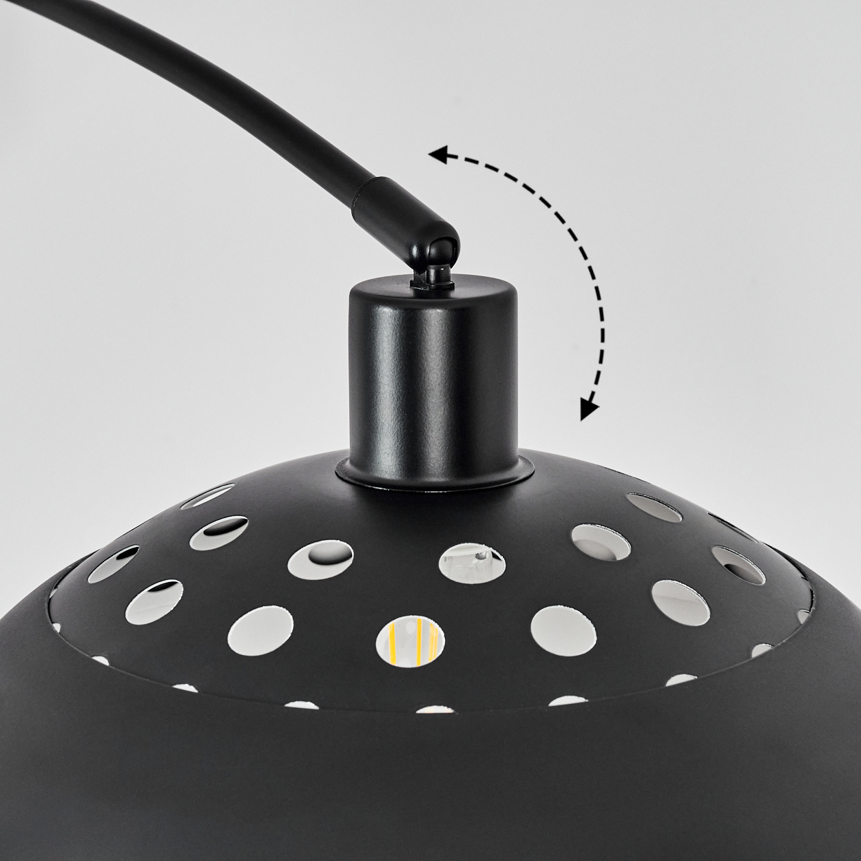 Nahaufnahme einer schwarzen Lampe mit gebogenem Arm. Der Lampenschirm hat Löcher. Ein Pfeil zeigt die Bewegung des Lampenkopfes an.