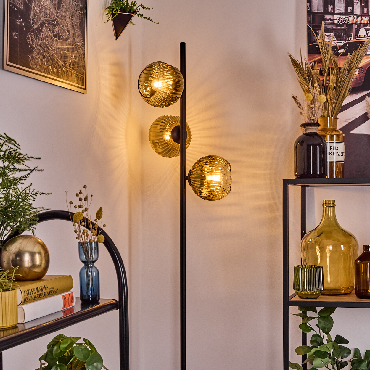 Ein modernes Wohnzimmer mit einer Stehlampe mit drei Kugelschirmen, Regalen mit Dekorationen und einer Karte an der Wand.