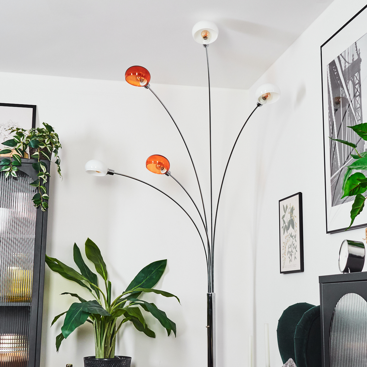 Eine moderne Stehlampe mit orangefarbenen und weißen Kugelleuchten steht in der Nähe von Pflanzen und gerahmter Kunst in einem weiß getünchten Raum.