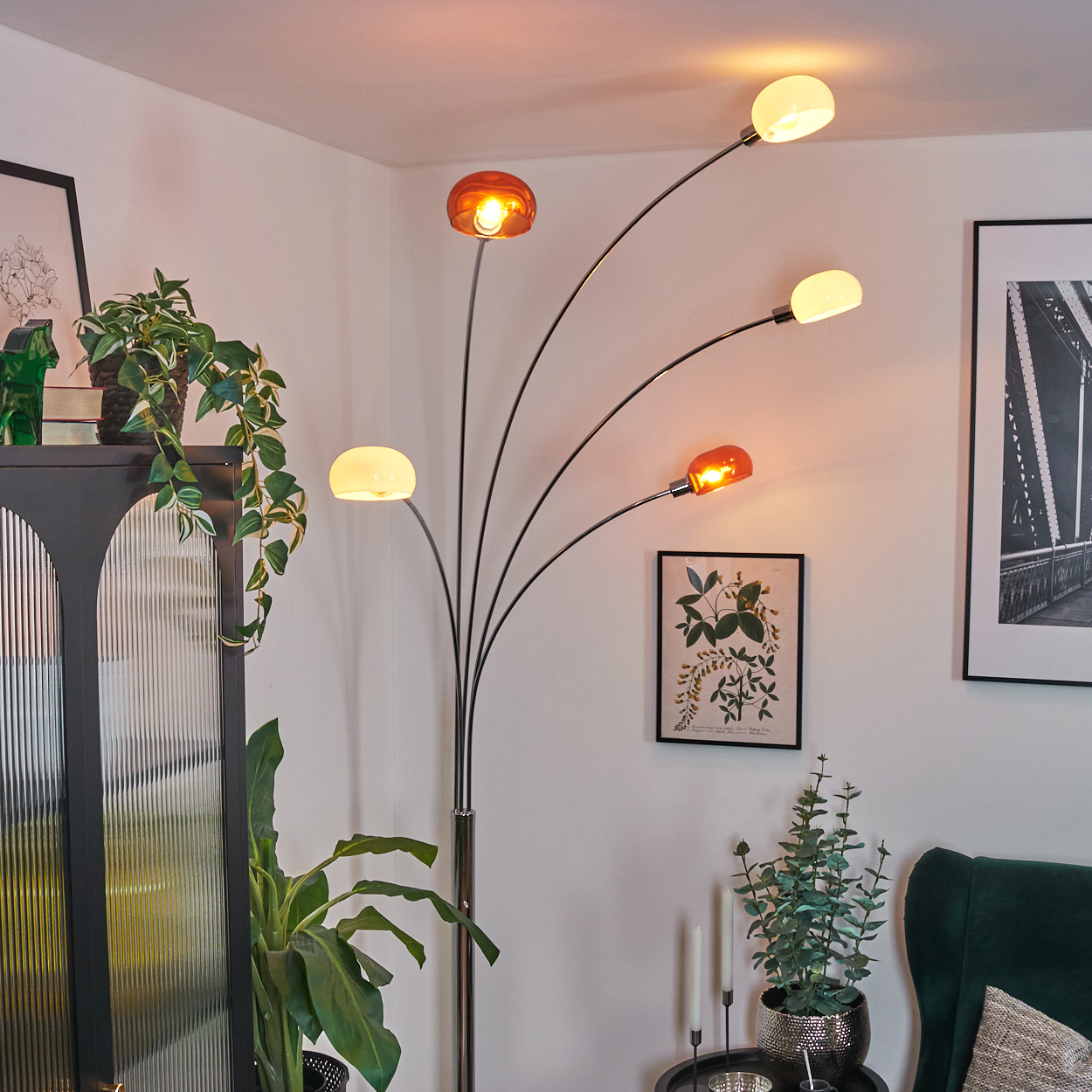 Ein modernes Wohnzimmer mit einer Stehlampe mit orangefarbenen und weißen Kugelleuchten. Pflanzen und Bilder sind ebenfalls im Raum.