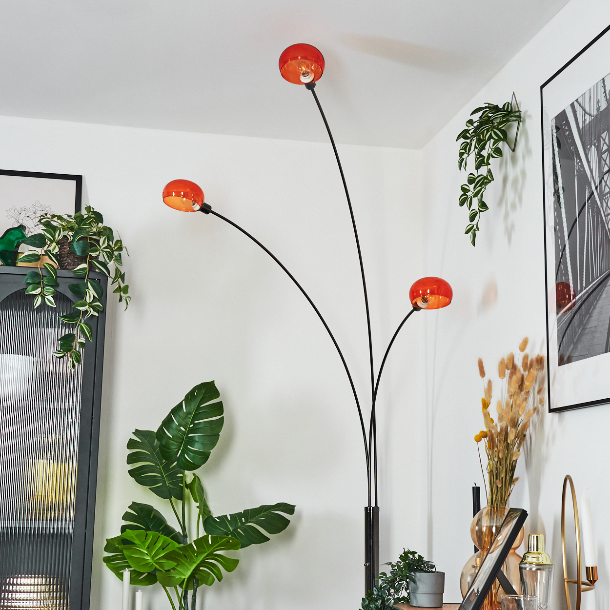 Ein modernes Wohnzimmer mit einer schwarz-orangenen Lampe. Pflanzen und gerahmte Kunstwerke schaffen ein stilvolles Interieur.