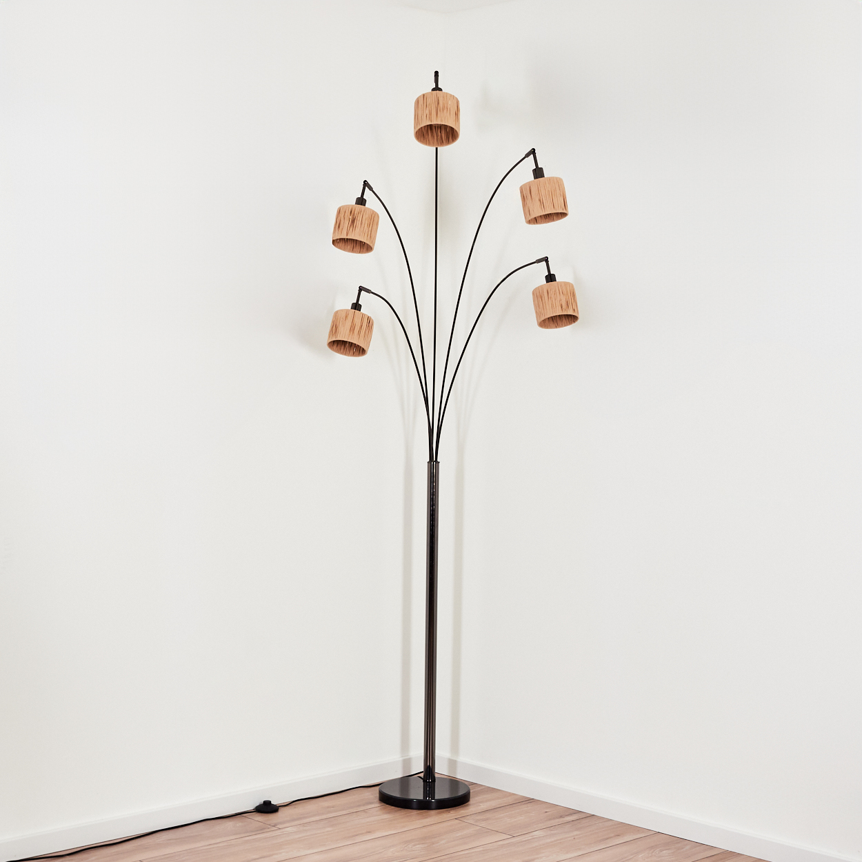Eine moderne Stehlampe mit fünf Lampenschirmen. Die Lampe ist schwarz mit Holzschirmen. Sie steht in einer weißen Ecke auf Holzboden.
